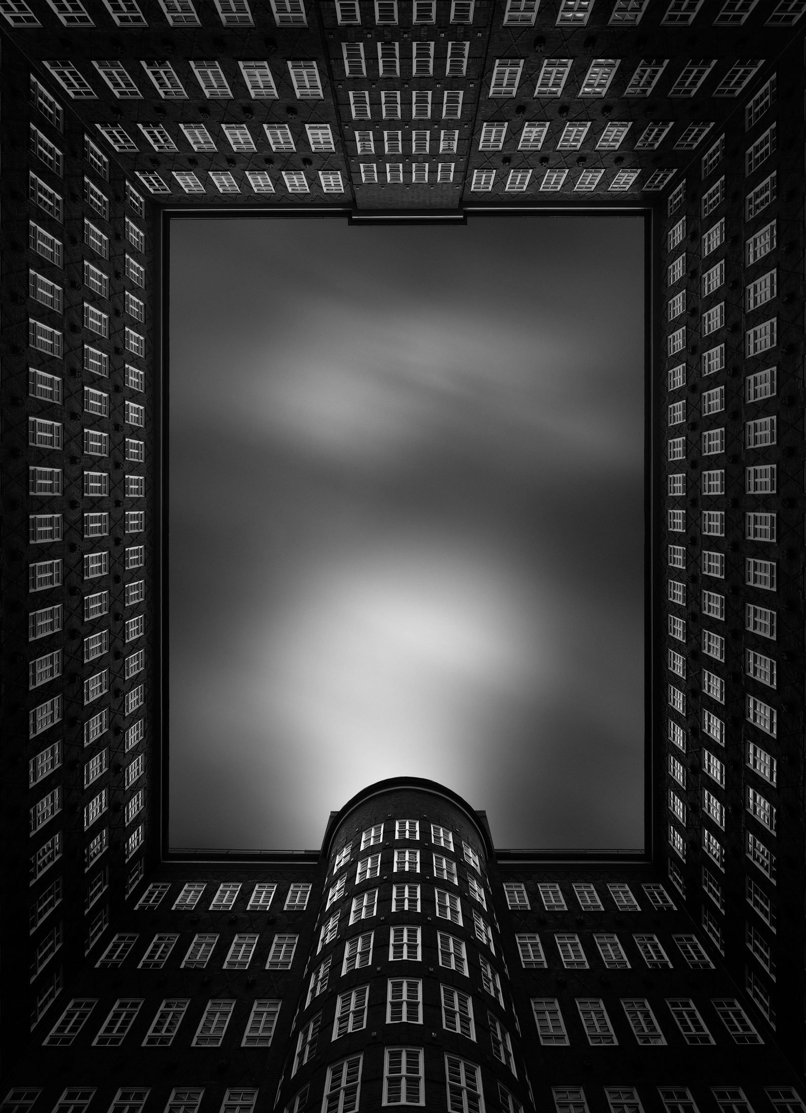 [architecture] [europe] [hamburg] [blackandwhite] Sprinkenhof Hamburg courtyard from below, rich dark brick facades densely framing a perfect rectangle of long-exposure Architectural Photography by Jim Scott.