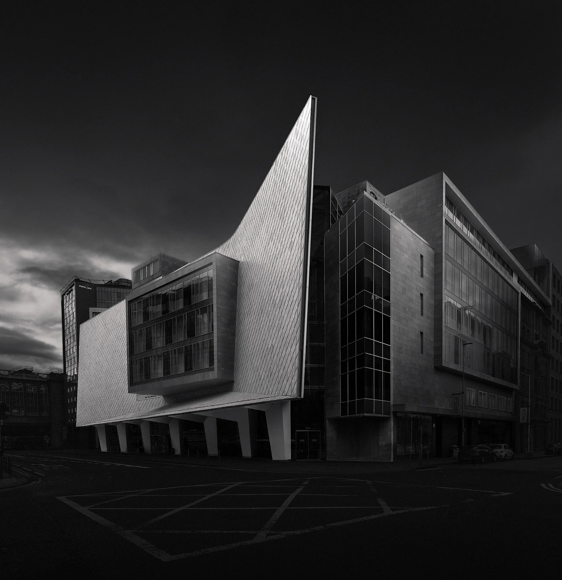 [architecture] [uk] [glasgow] [blackandwhite] [square] Radisson Blu Glasgow, striking zinc-clad diagonal fin sweeping upward from a low dark base viewed from a corner position Architectural Photography by Jim Scott.