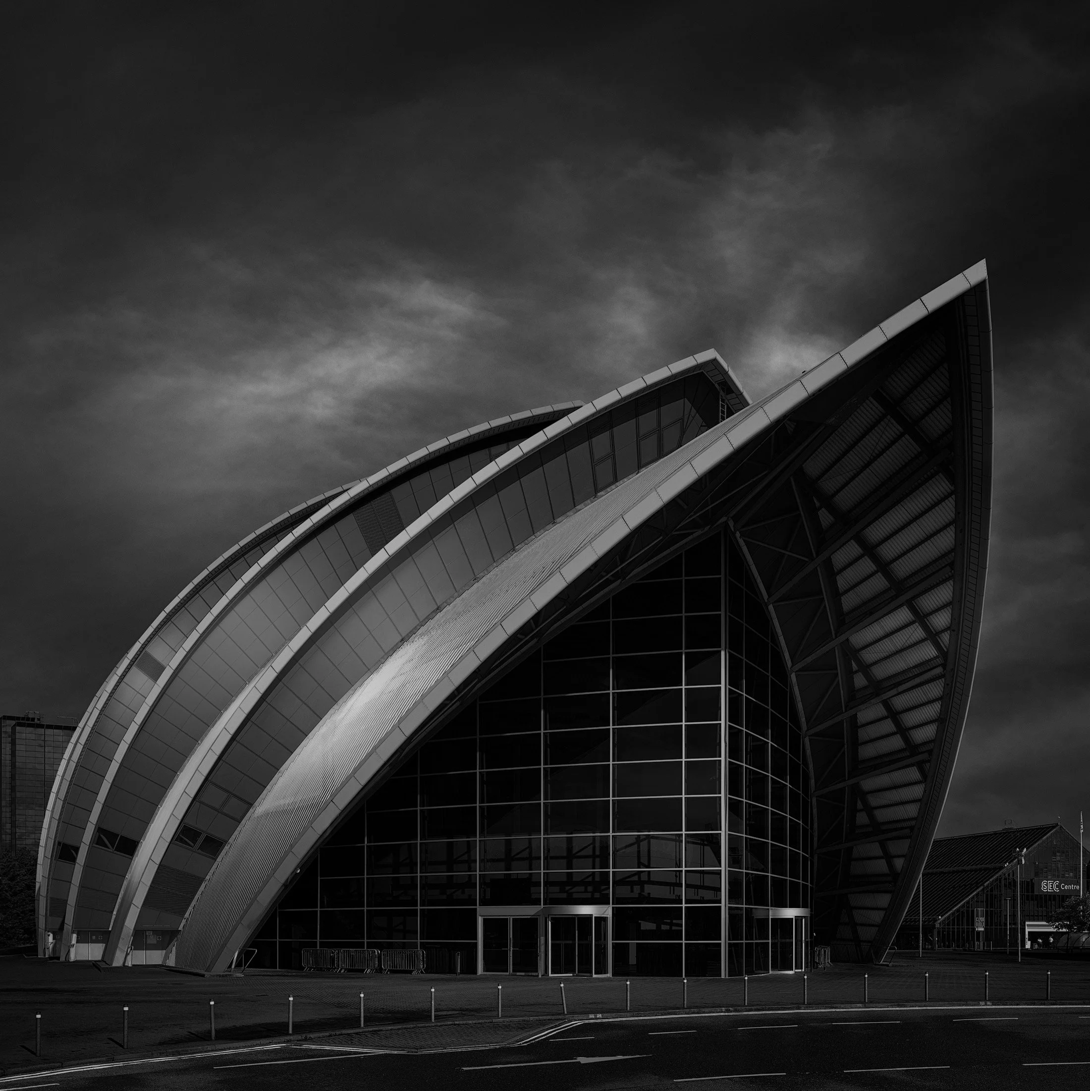 Contemporary landmark architecture in Glasgow, Scotland: A dramatic monochrome study of the SEC Armadillo (Clyde Auditorium), designed by Foster + Partners. This architectural photograph highlights the building's iconic overlapping "ship hull" geomet