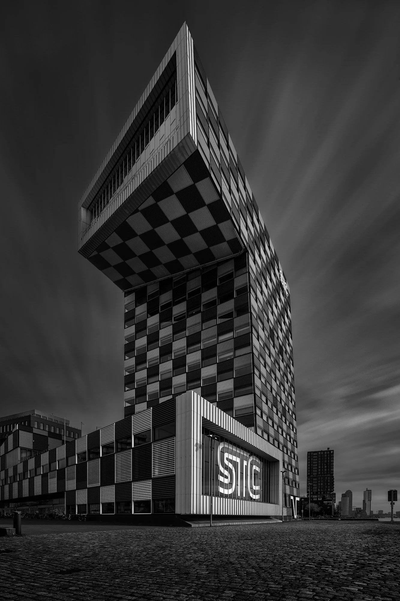 [architecture] [europe] [rotterdam] [blackandwhite] 17:43Claude responded: Monochrome long-exposure, STC Group Rotterdam, checkerboard façade cantilevering over the waterfront.Monochrome long-exposure, STC Group Rotterdam, checkerboard façade can