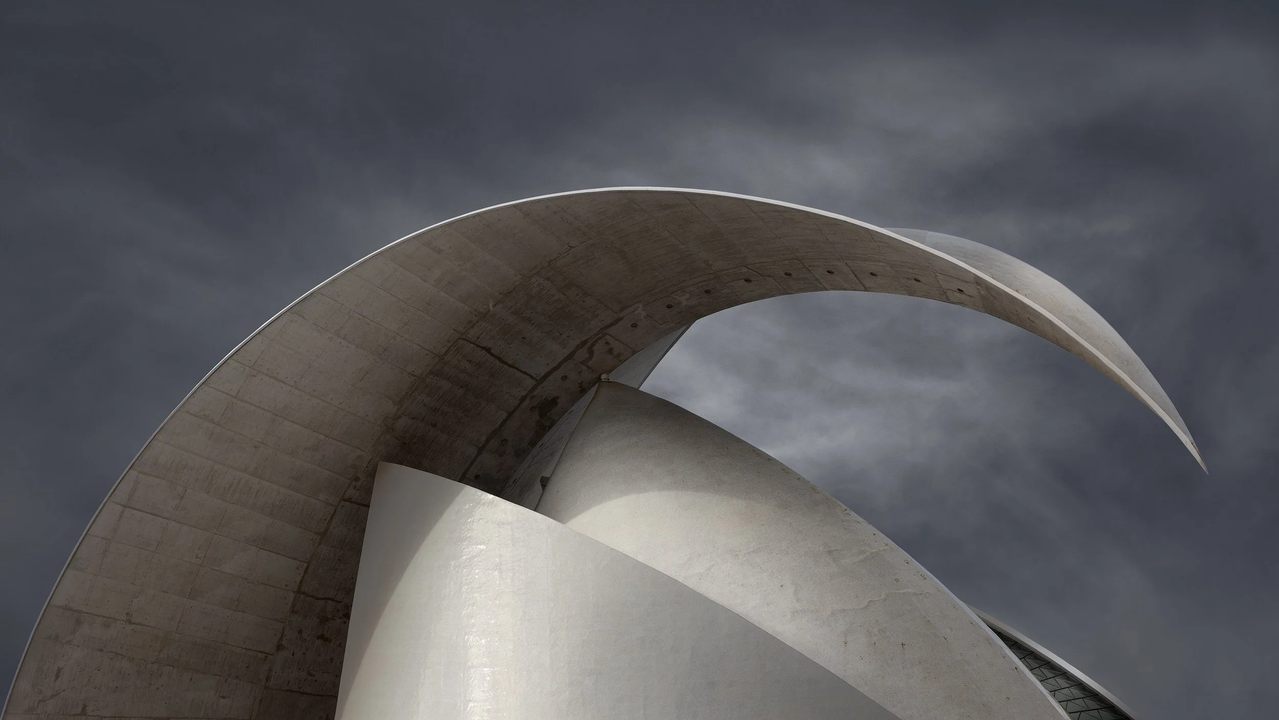 [architecture] [europe] [santacruzdetenerife] [colour] [panoramic] Calatrava's Auditorio de Tenerife, sweeping concrete crescent arch soaring against a dramatic stormy sky. Architectural Photography by Jim Scott.