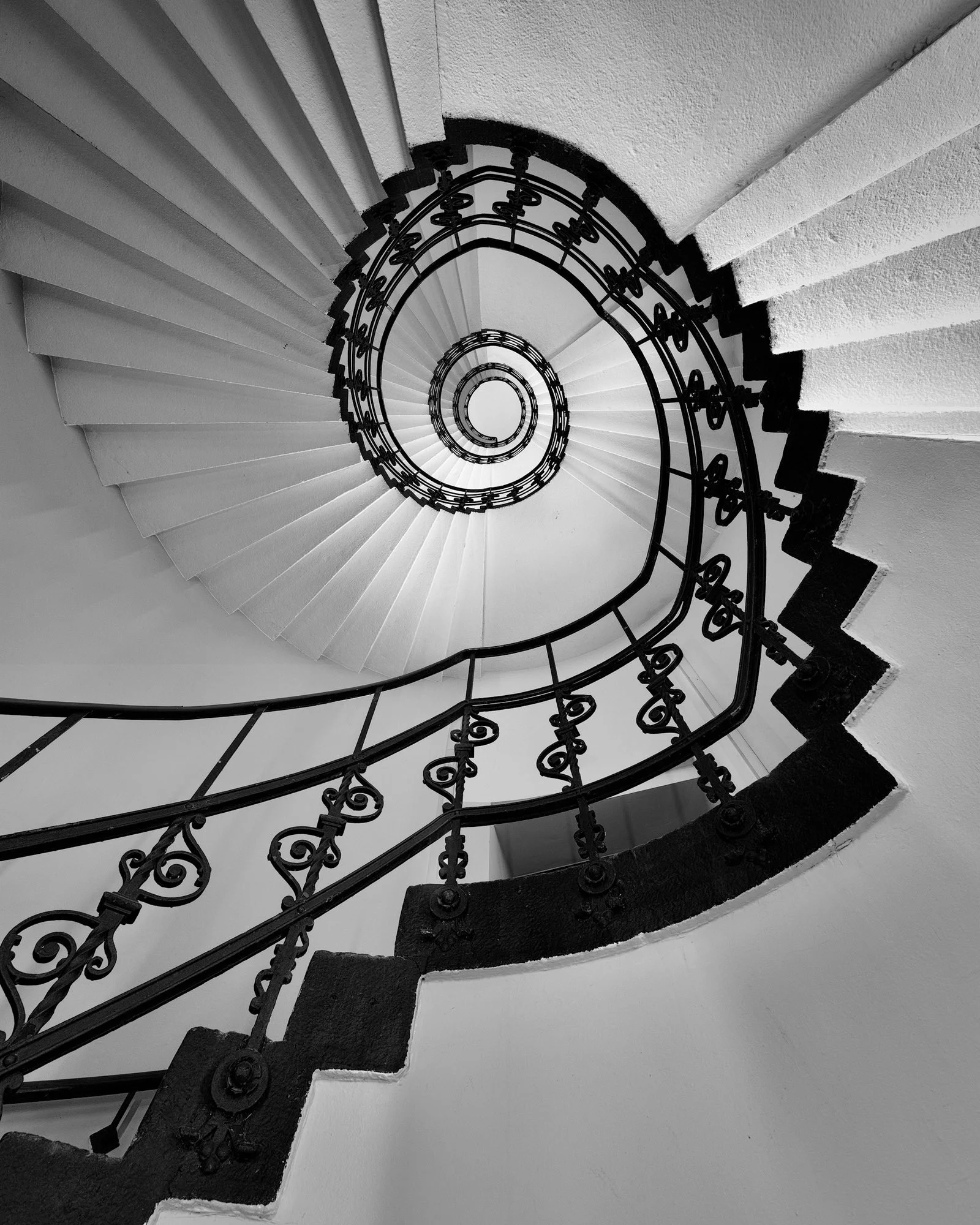 [architecture] [europe] [hamburg] [blackandwhite] [internal] Alte Oberpostdirektion Hamburg staircase, ornate black ironwork balustrade spiralling upward to a bright oval oculus. Architectural Photography by Jim Scott.