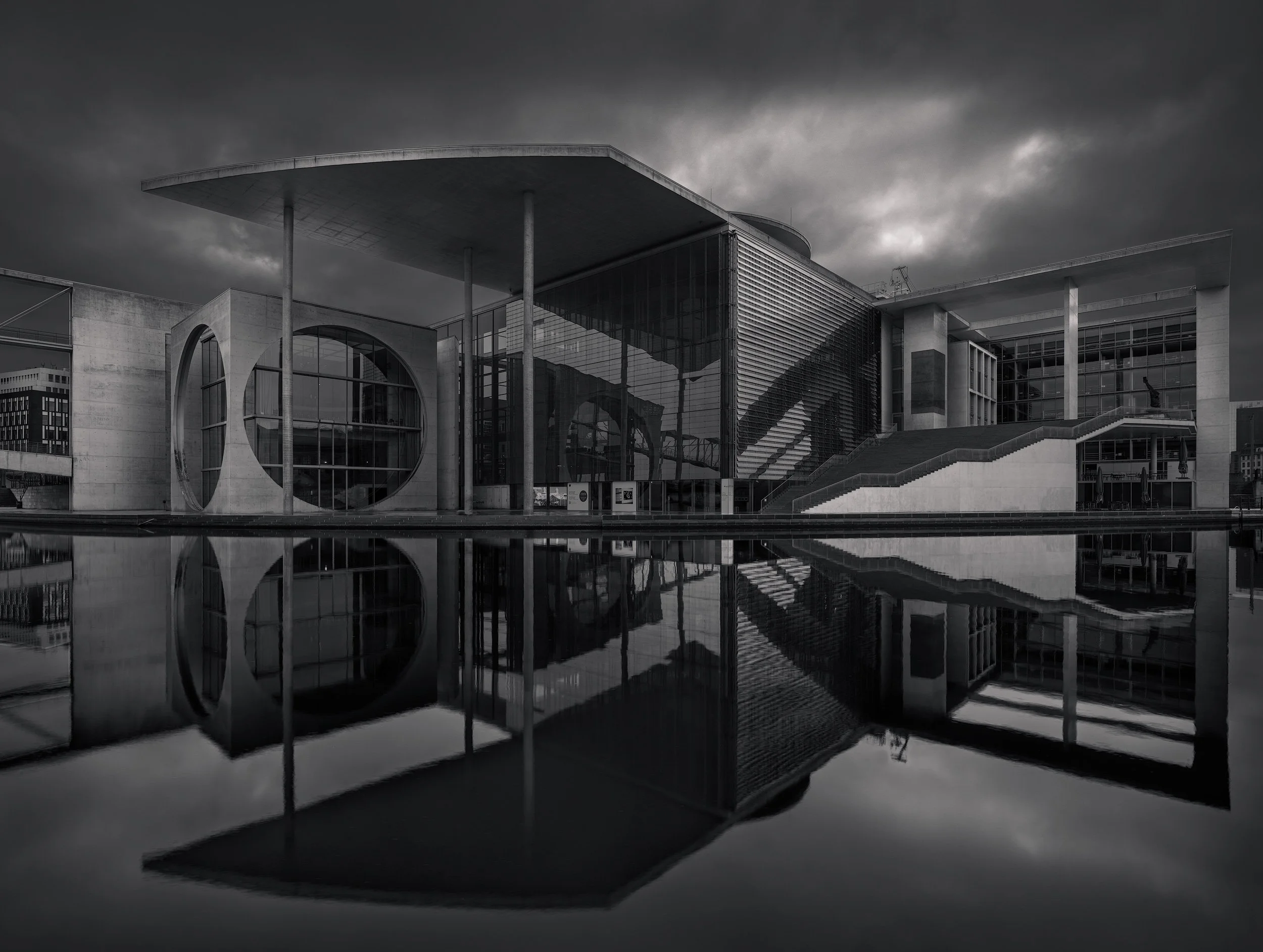 [architecture] [europe] [berlin] [blackandwhite] Berlin Government District B&W long exposure, circular windows and concrete canopy mirrored in a still dark pool. Architectural Photography by Jim Scott.
