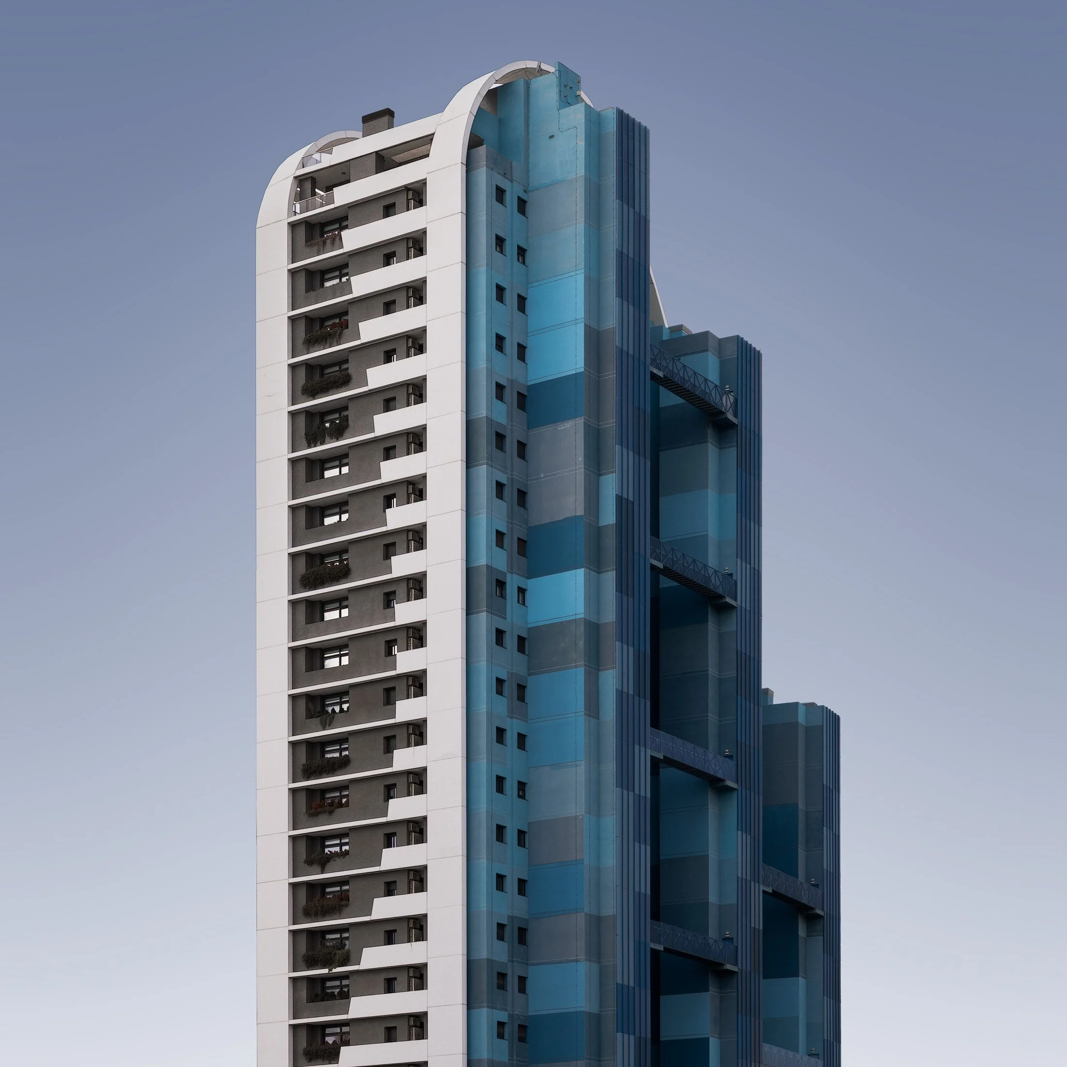 [architecture] [europe] [benidorm] [colour] [square] Benidorm residential tower, white concrete frame and stepped teal blue glass panels rising against a pale clear sky. Architectural Photography by Jim Scott.