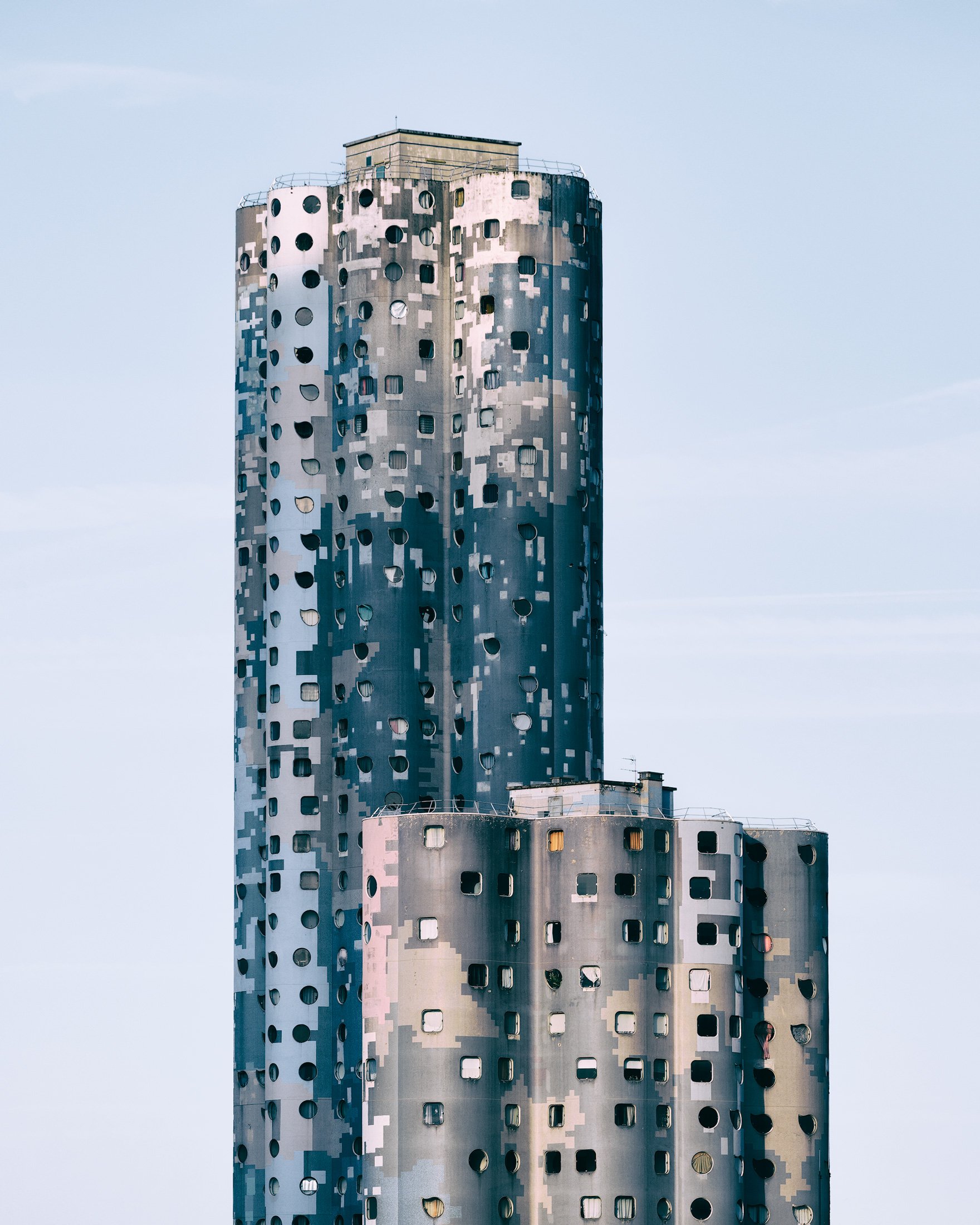 [architecture] [europe] [paris] [colour] Tours Aillaud Nanterre Paris, two cylindrical towers with pixelated grey-blue camouflage skin and circular windows. Architectural Photography by Jim Scott.