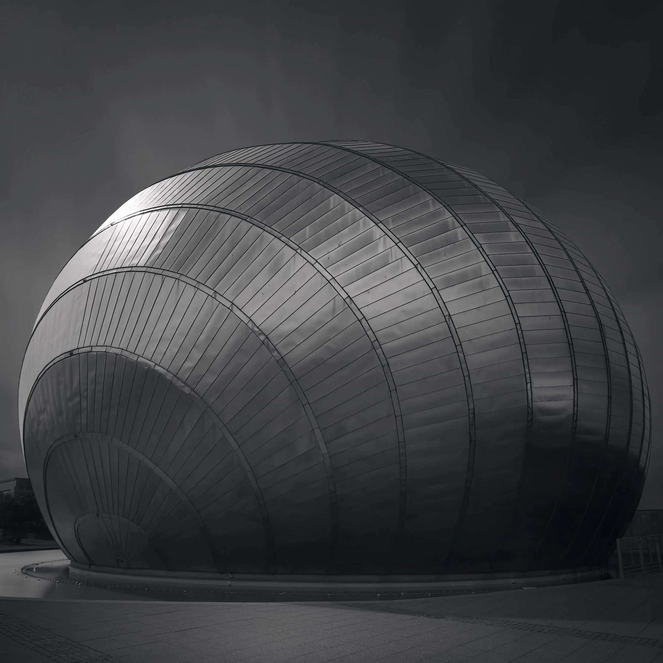 High-tech architecture in Glasgow: The IMAX Cinema at the Glasgow Science Centre, designed by BDP (Building Design Partnership). A dramatic black and white architectural study of the building’s sharp, angular titanium cladding and metallic textures, 