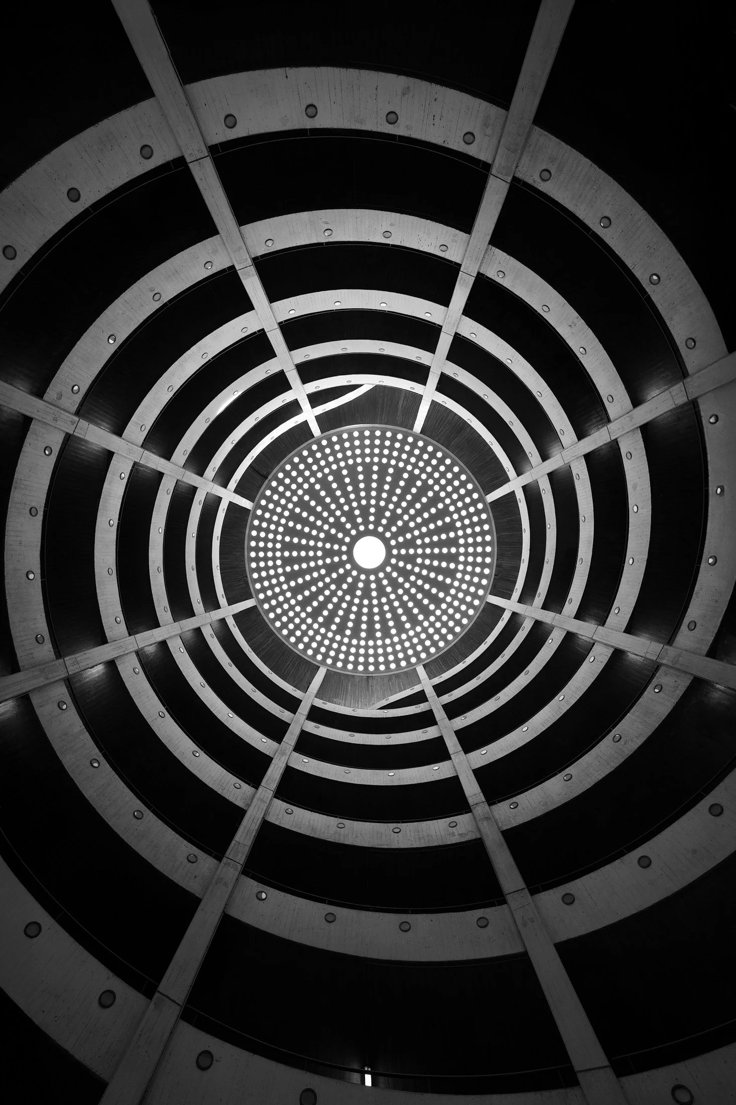 [architecture] [europe] [hamburg] [blackandwhite] [internal] Rodingsmarkt Hamburg car park dome, looking up through concentric concrete rings to central illuminated oculus, monochrome. Architectural Photography by Jim Scott.