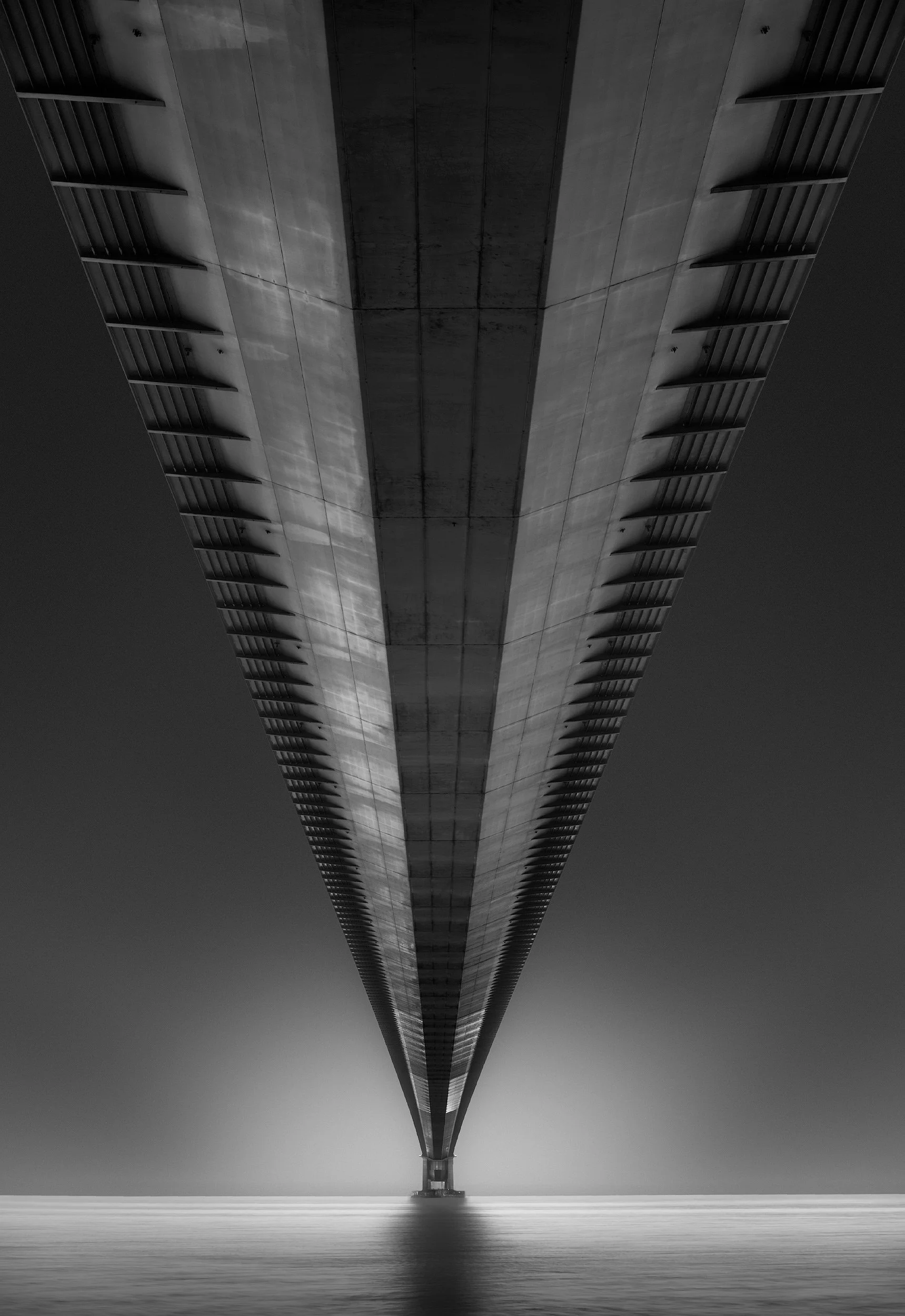 [architecture] [uk] [hull] [blackandwhite] Humber Bridge underside monochrome, twin ribbed concrete decks converging to a single vanishing point above the estuary. Architectural Photography by Jim Scott.