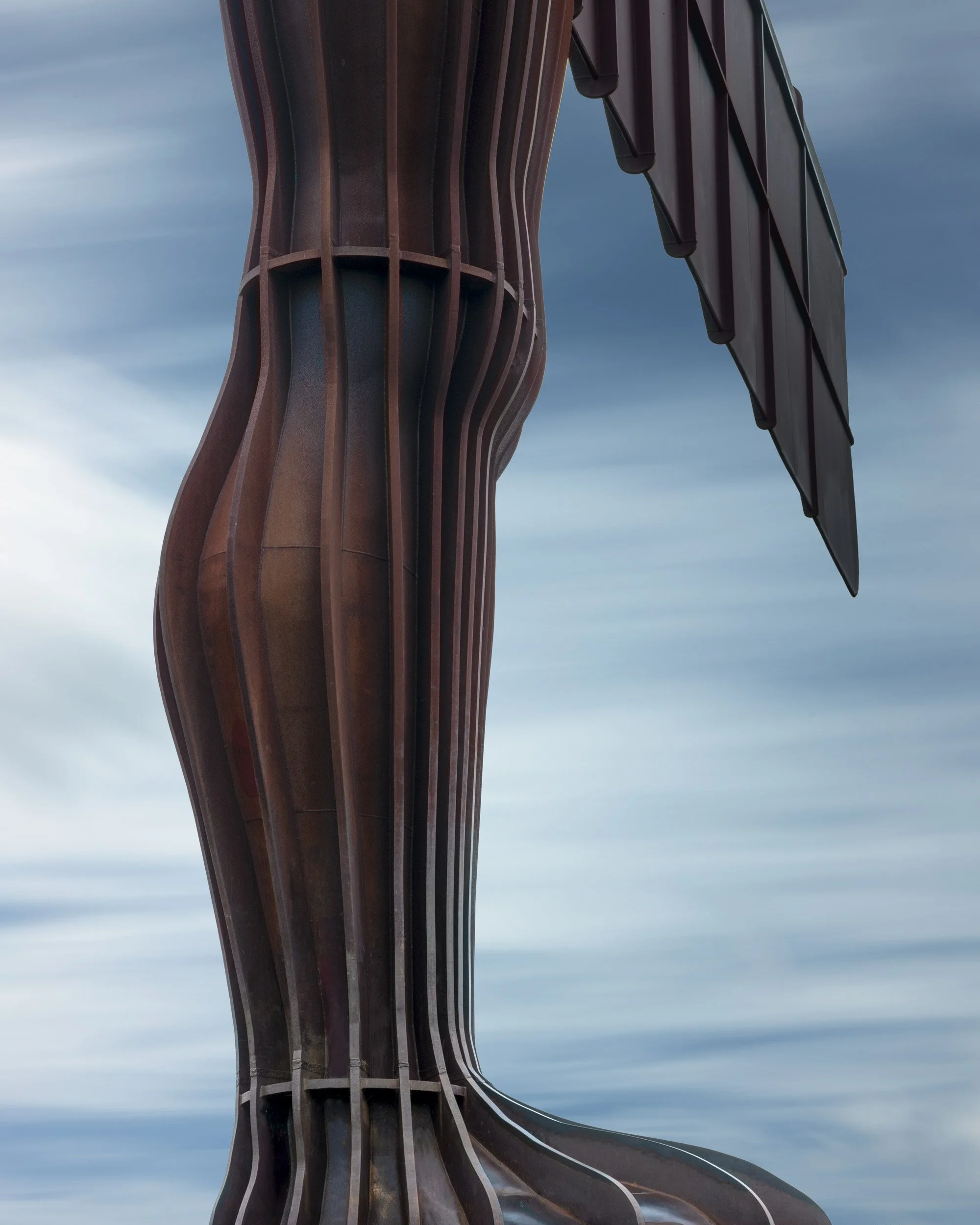 Contemporary public sculpture in Gateshead, UK: A detailed study of the Angel of the North, designed by Antony Gormley. This long-exposure photograph captures the rhythmic vertical ribs and weathered COR-TEN steel texture of the statue's lower torso 