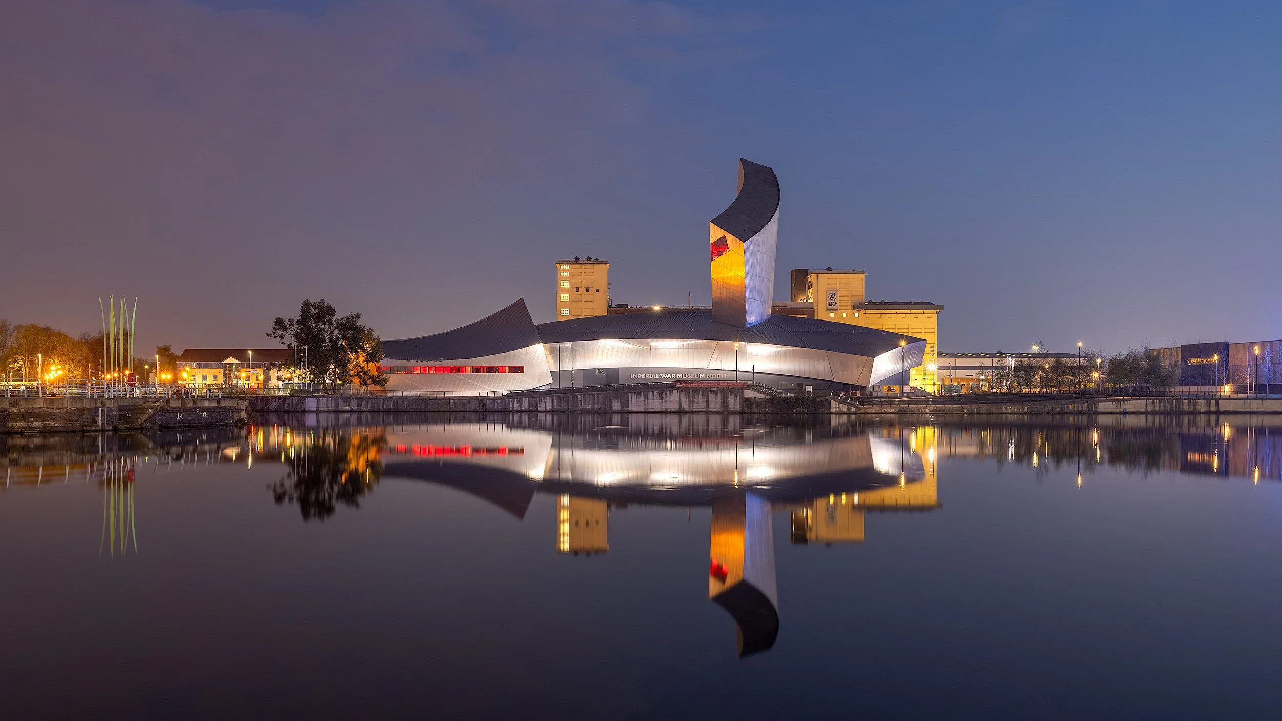 [architecture] [uk] [salford] [colour] [panoramic] [nightscape] IWM North Salford at blue hour, Daniel Libeskind's steel shards reflected in the still Manchester Ship Canal. Architectural Photography by Jim Scott.