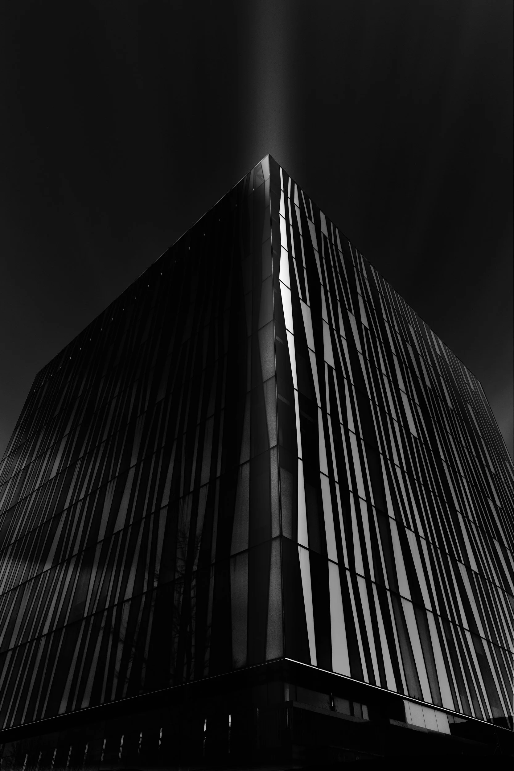 Contemporary academic architecture in Aberdeen, Scotland: A dramatic monochromatic study of the Sir Duncan Rice Library, designed by Schmidt Hammer Lassen. This architectural photograph captures the library's iconic irregular-patterned glass facade a