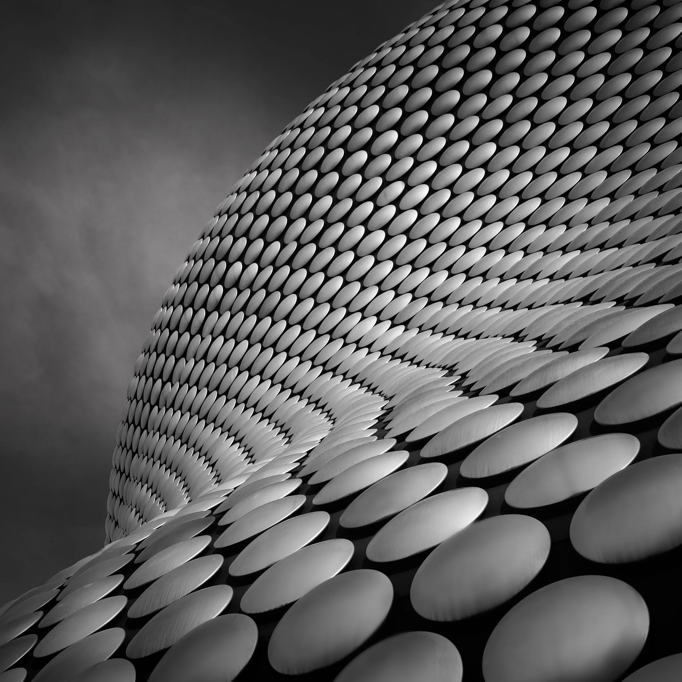 Iconic blobitecture in Birmingham, UK: A dramatic monochromatic study of the Selfridges building façade, designed by Future Systems. This dynamic architectural photograph captures the rhythmic repetition of thousands of aluminium discs across the bui