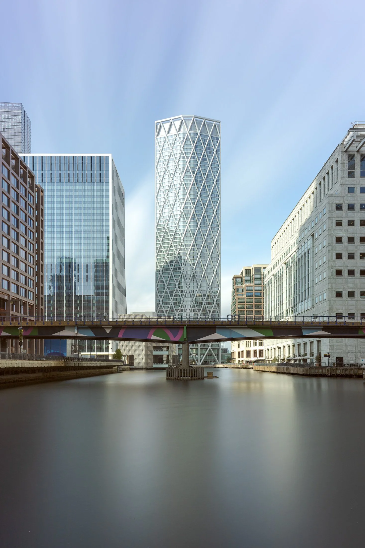 [architecture] [uk] [london] [colour] Newfoundland tower Canary Wharf, diamond-lattice cylindrical form rising above Middle Dock and the DLR bridge. Architectural Photography by Jim Scott.