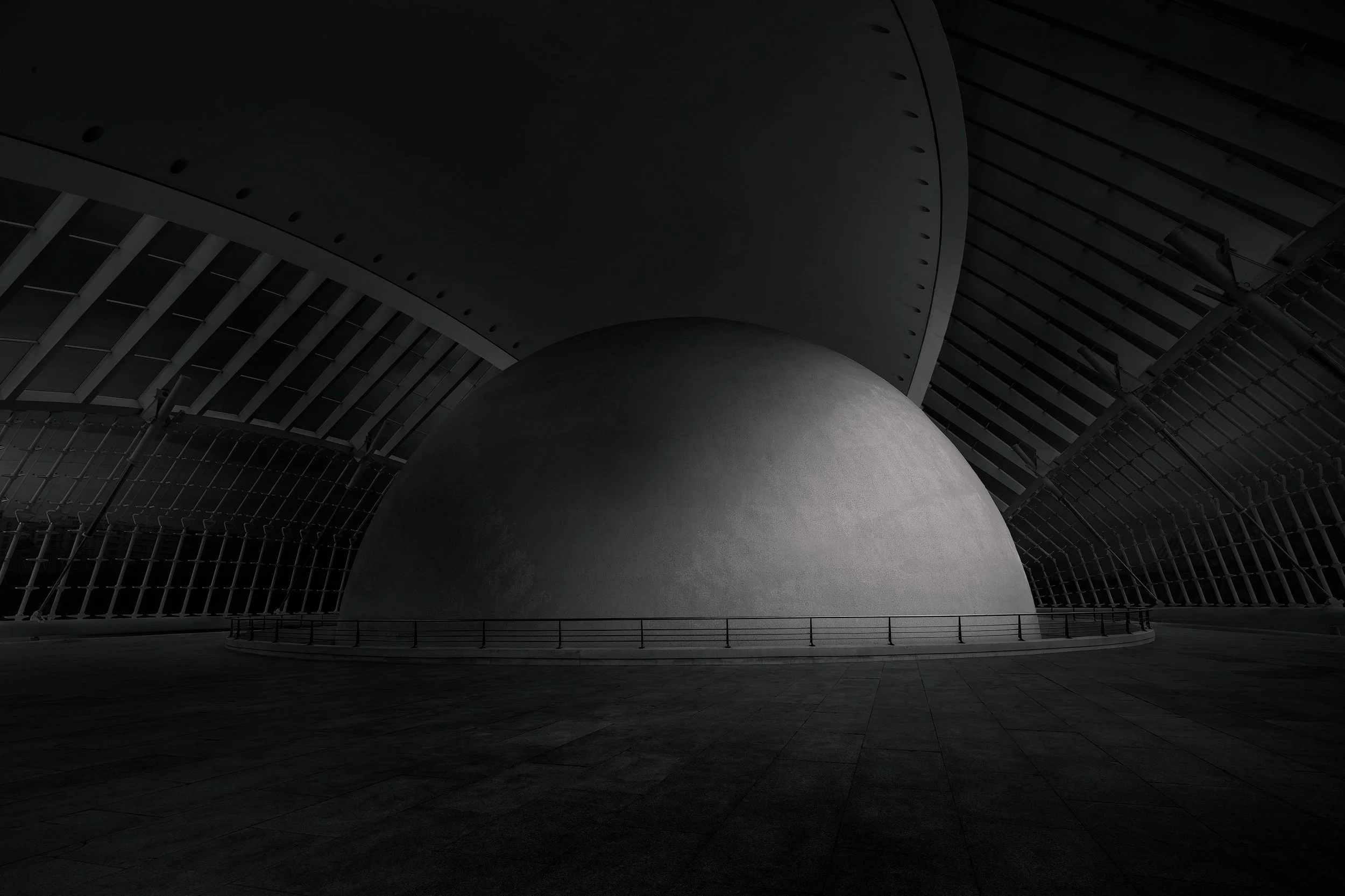 Futuristic cultural architecture in Valencia, Spain: A monochromatic interior study of L’Hemisfèric at the City of Arts and Sciences, designed by Santiago Calatrava. This photograph highlights the colossal OMNIMAX cinema dome framed by the rhythmic, 