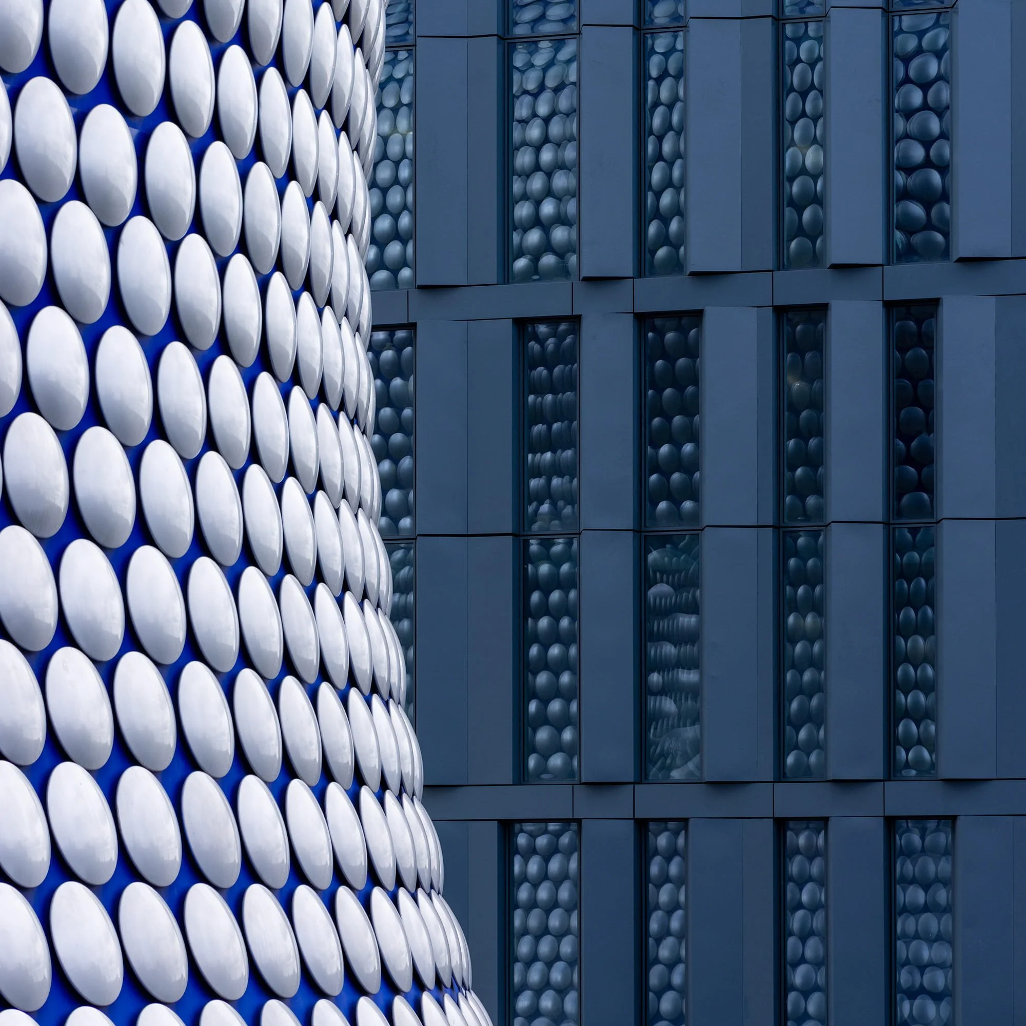 [architecture] [uk] [birmingham] [colour] [square] [abstract] Selfridges Birmingham Bullring close detail, polished aluminium discs meeting an embossed dark blue bubble-panel facade. Architectural Photography by Jim Scott.