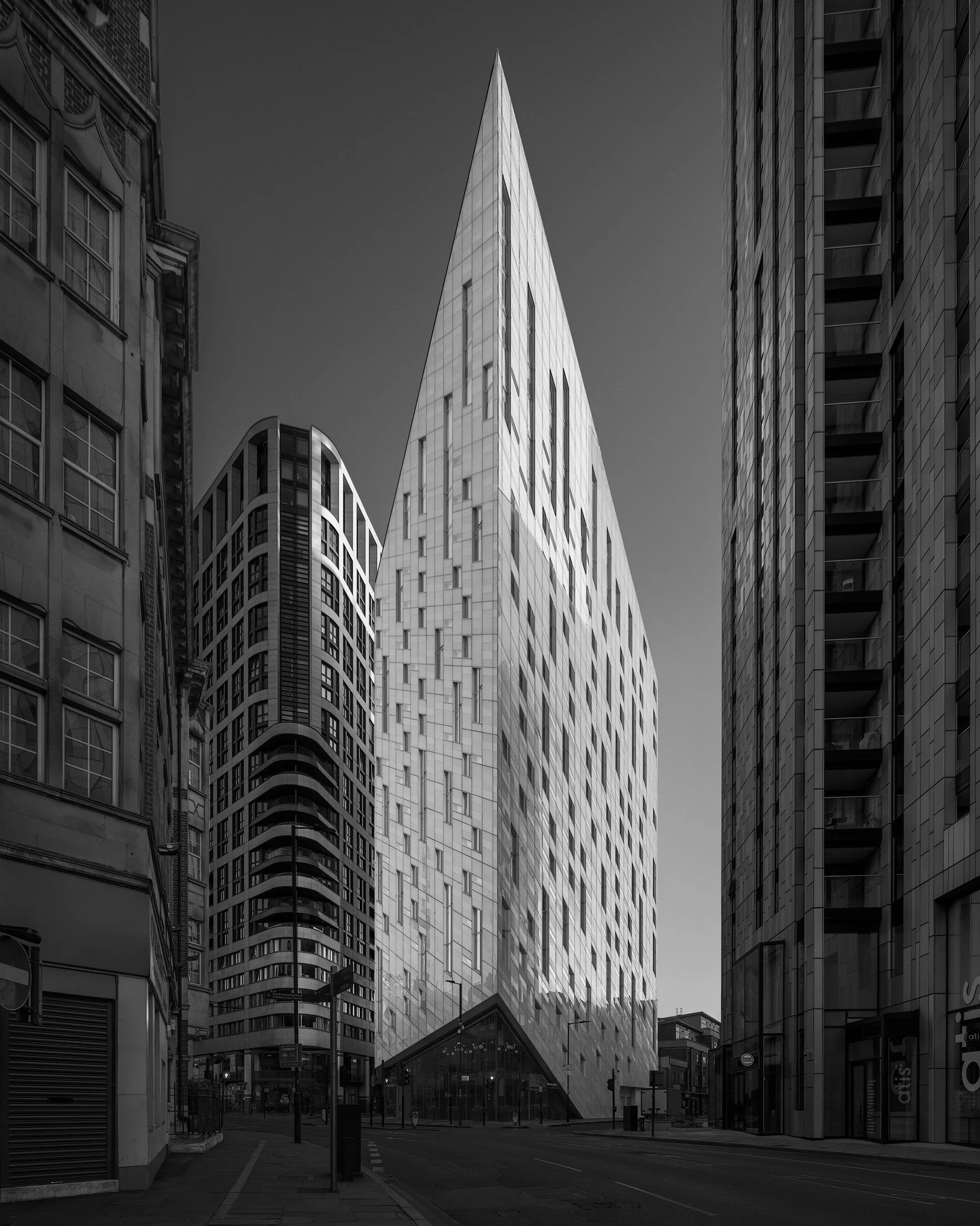 Contemporary hospitality architecture in Shoreditch, London: A dramatic monochromatic study of the Montcalm East hotel, designed by Squire & Partners. This architectural photograph captures the building’s striking, sharp-edged form, inspired by the o