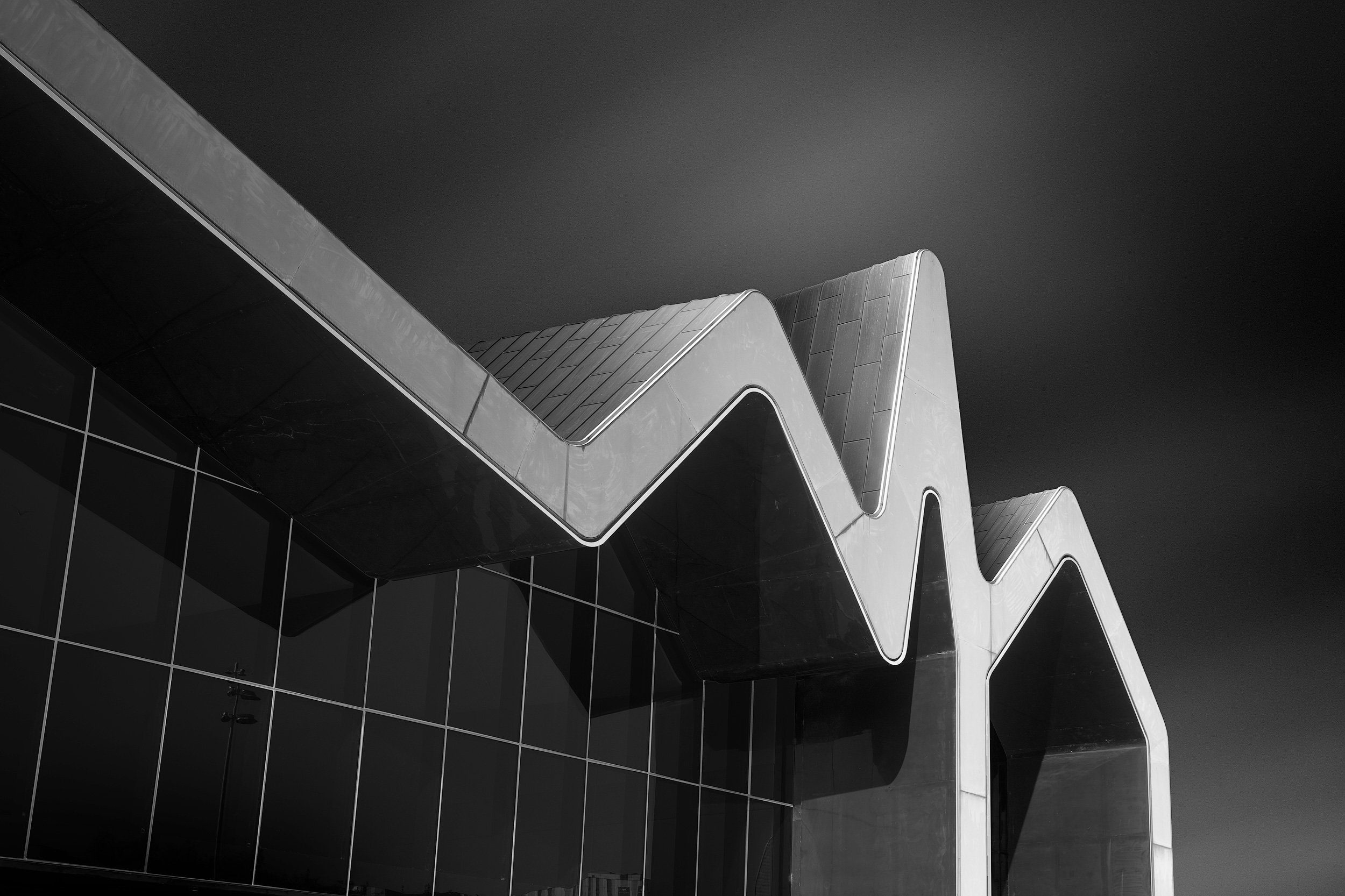 [architecture] [uk] [glasgow] [blackandwhite] Riverside Museum Glasgow waterfront, Zaha Hadid's full deconstructivist facade with white zigzag roofline. Architectural Photography by Jim Scott.