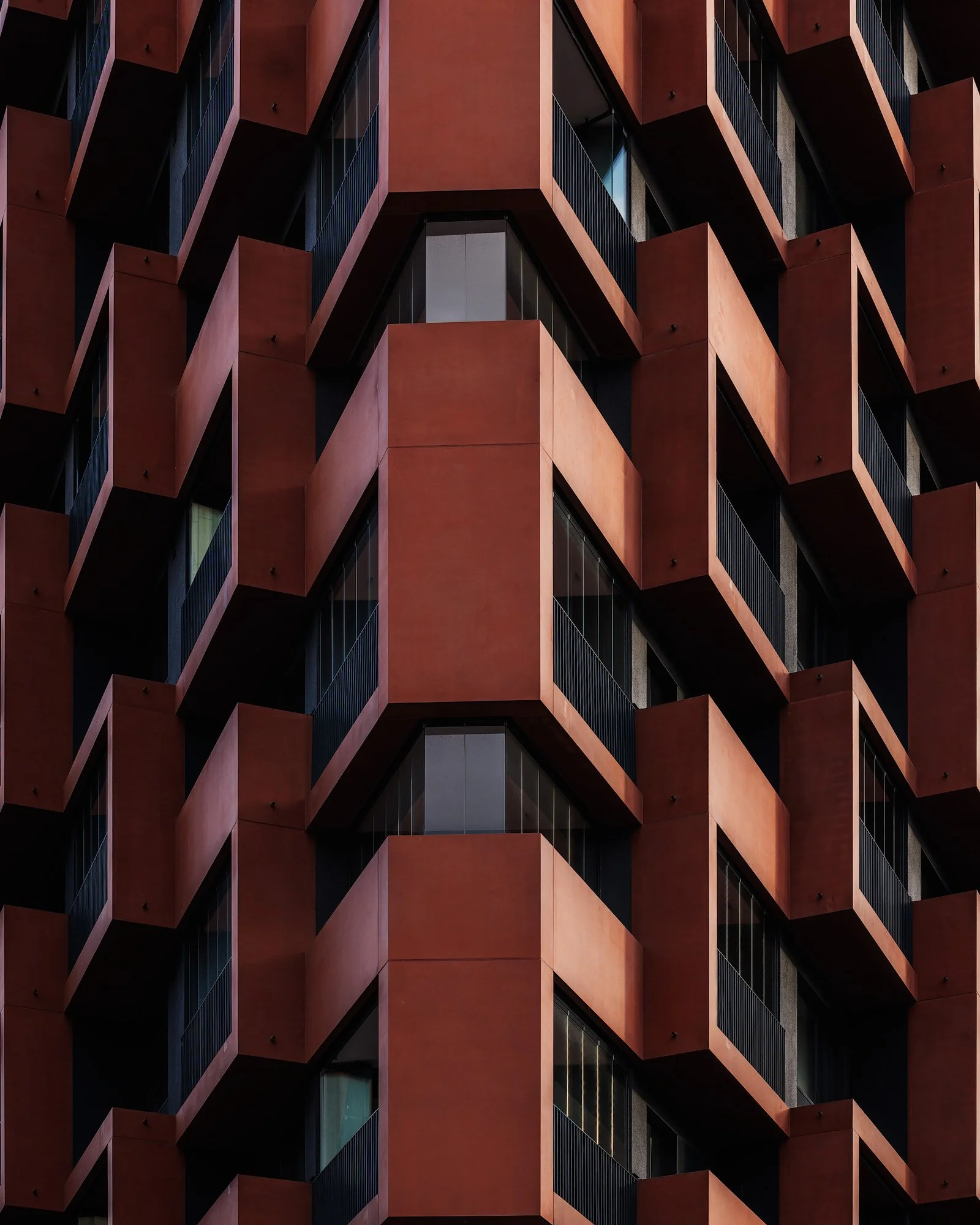 [architecture] [colour] [europe] [hamburg] [abstract] Close-up of Eleven Decks HafenCity Hamburg, red concrete balconies casting deep angular shadows. Architectural Photography by Jim Scott.
