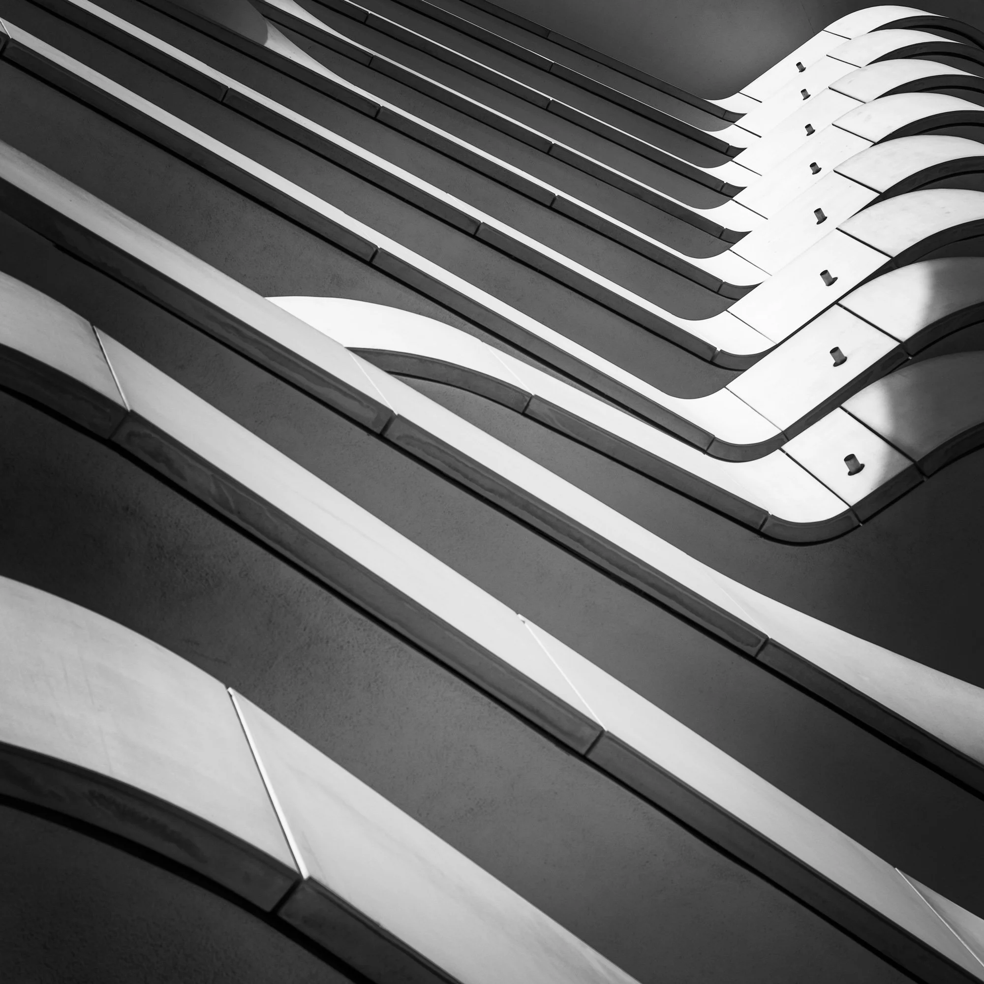 [architecture] [europe] [hamburg] [blackandwhite] [square] [abstract] Sweeping curved panels and repeating diagonal lines create an abstract architectural facade in strong light and shadow. Architectural Photography by Jim Scott