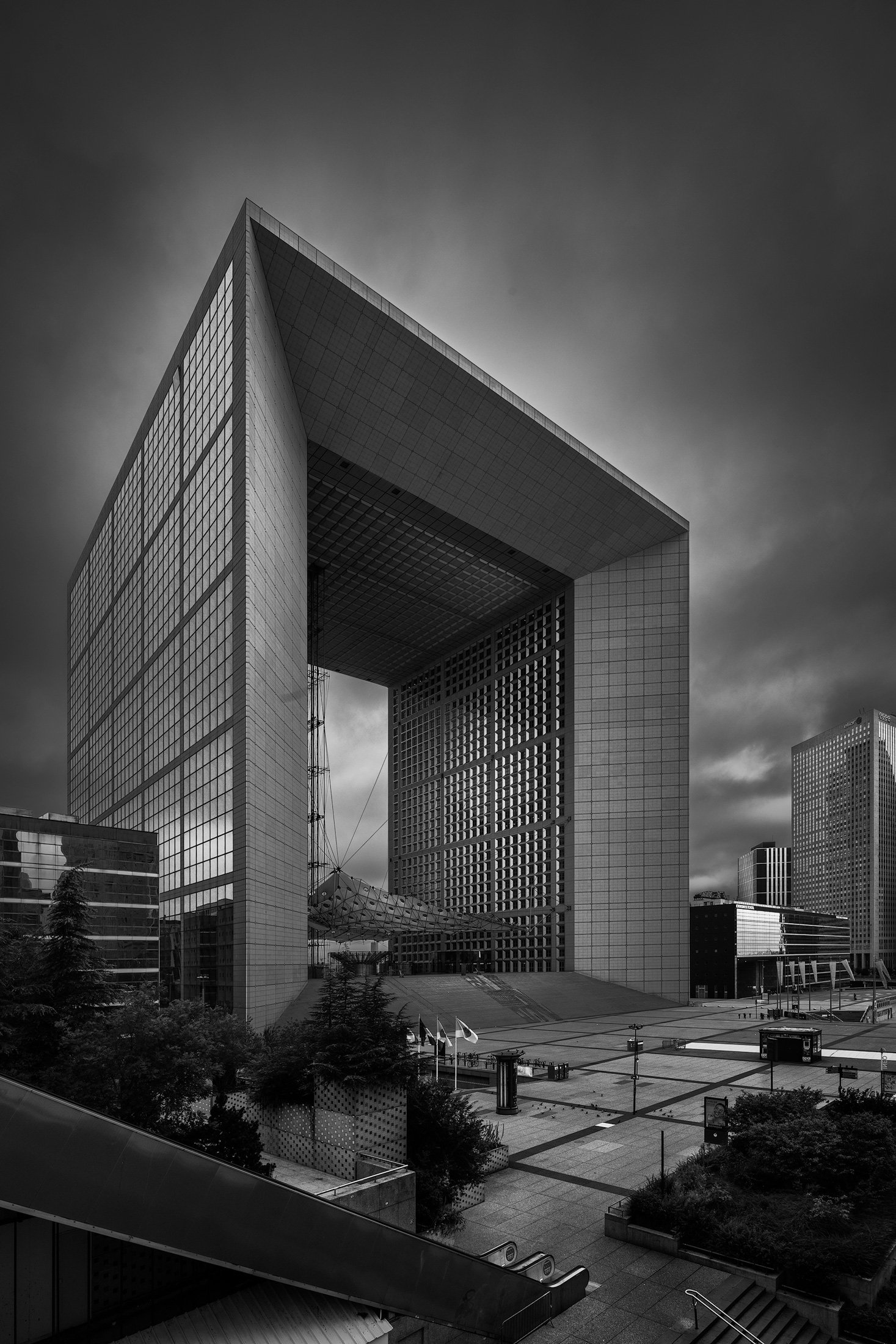 [architecture] [europe] [paris] [blackandwhite] Grande Arche La Défense Paris, colossal hollow cube office tower elevated view, surrounding business district, bold black and white. Architectural Photography by Jim Scott. 