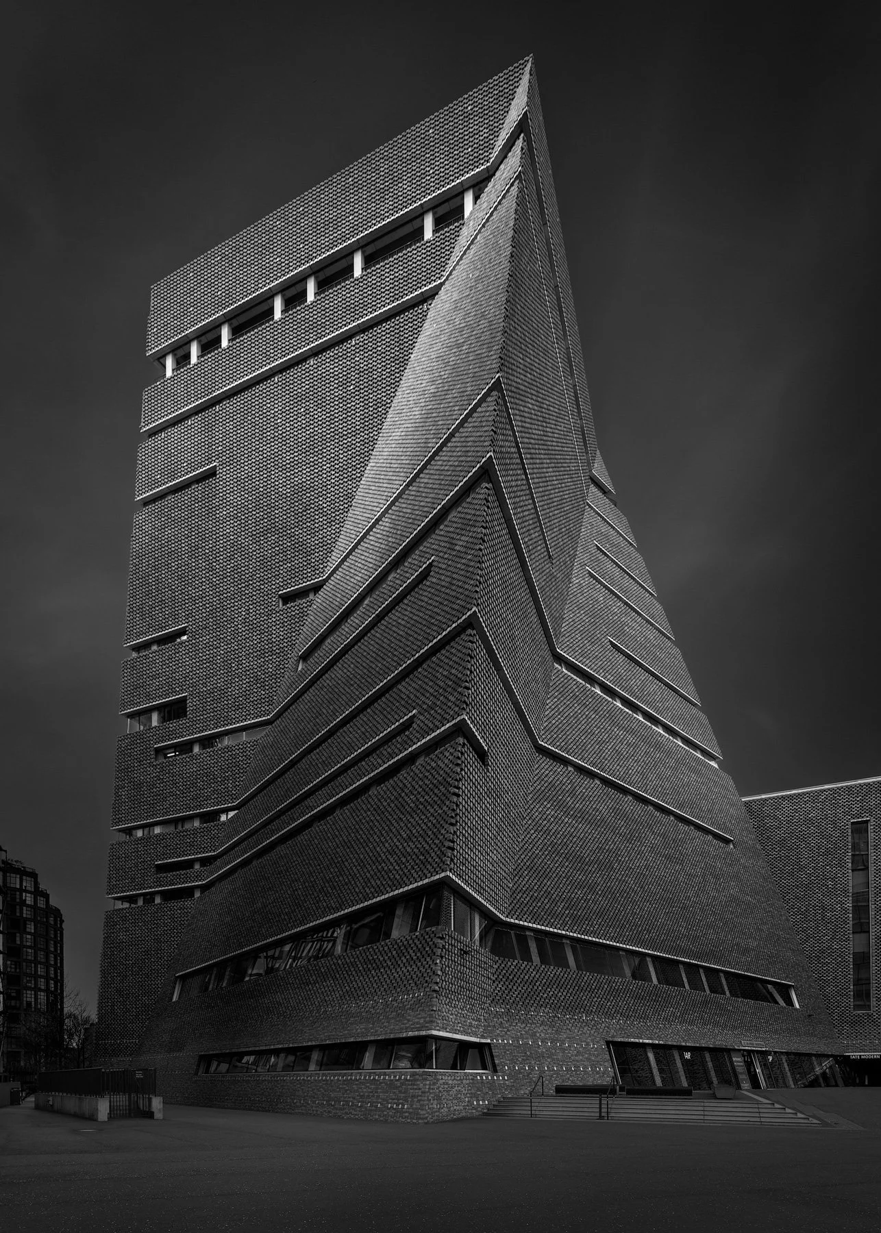 [architecture] [uk] [london] [blackandwhite] Blavatnik Building's angular brick façade rises against a moody London sky at Tate Modern. Architectural Photography by Jim Scott