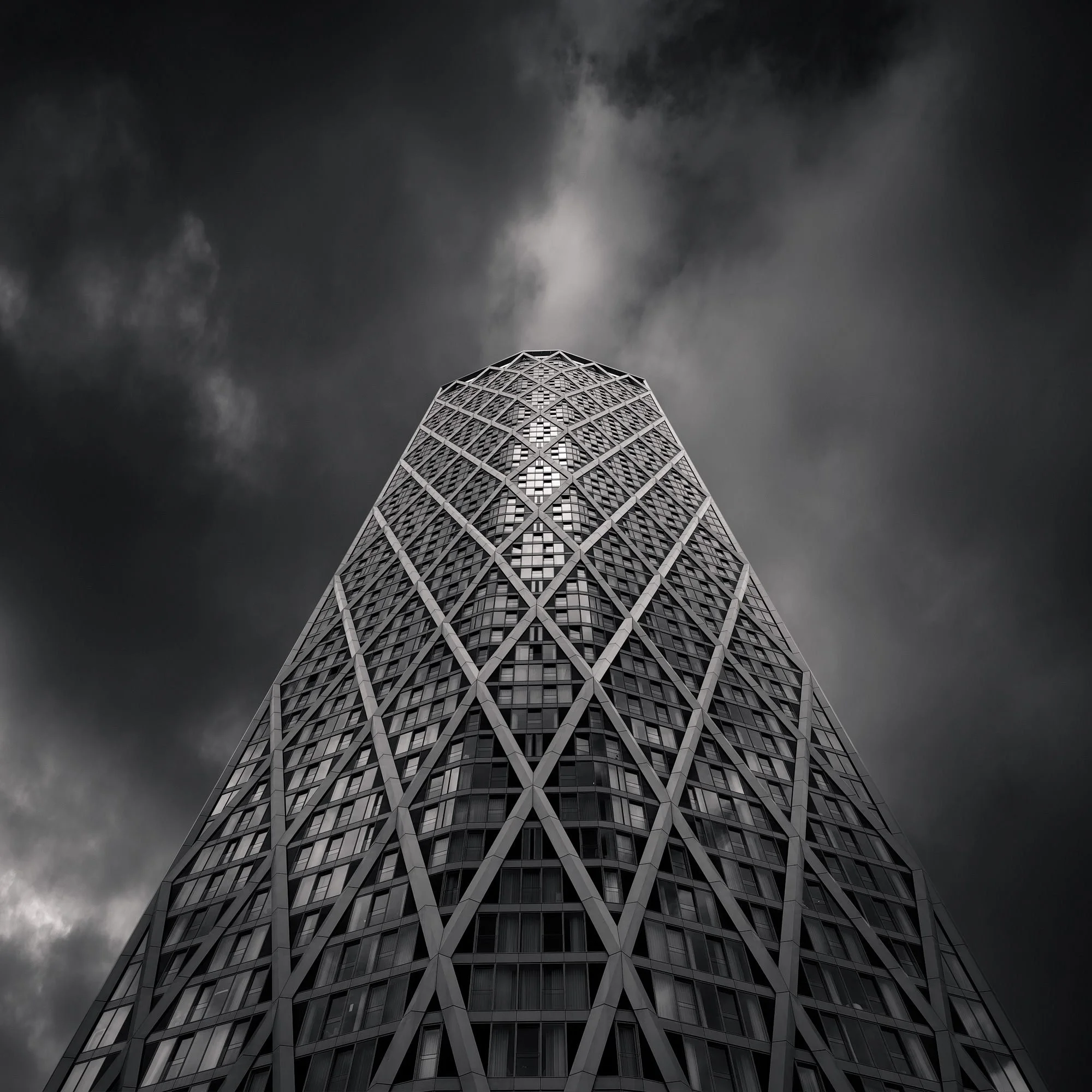 [architecture] [uk] [london] [blackandwhite] Newfoundland tower Canary Wharf B&W long exposure, full diagrid form soaring above the dock under a brooding storm sky. Architectural Photography by Jim Scott.