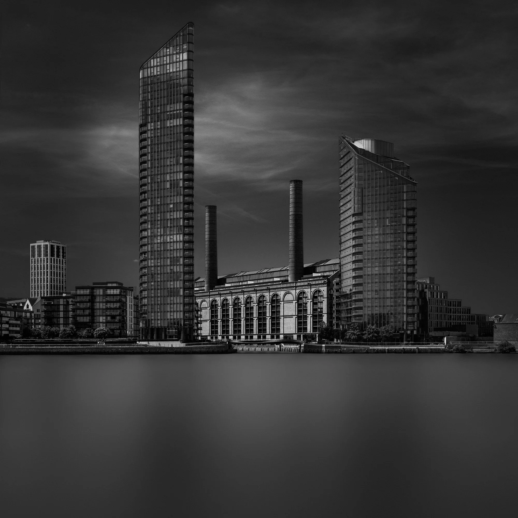 [architecture] [uk] [london] [blackandwhite] [square] Chelsea's Lots Road B&W long exposure from the Thames, old power station flanked by two tall tapered glass towers. Architectural Photography by Jim Scott.