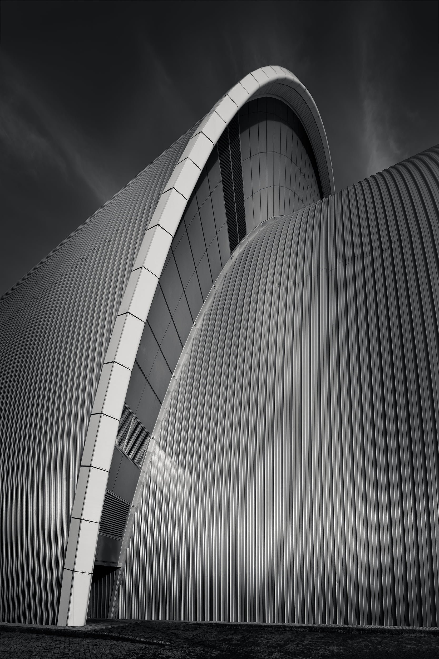 [architecture] [uk] [glasgow] [blackandwhite] Clyde Auditorium Glasgow dramatic upward shot, two interlocking stainless steel shells against a dark streaked sky. Architectural Photography by Jim Scott.