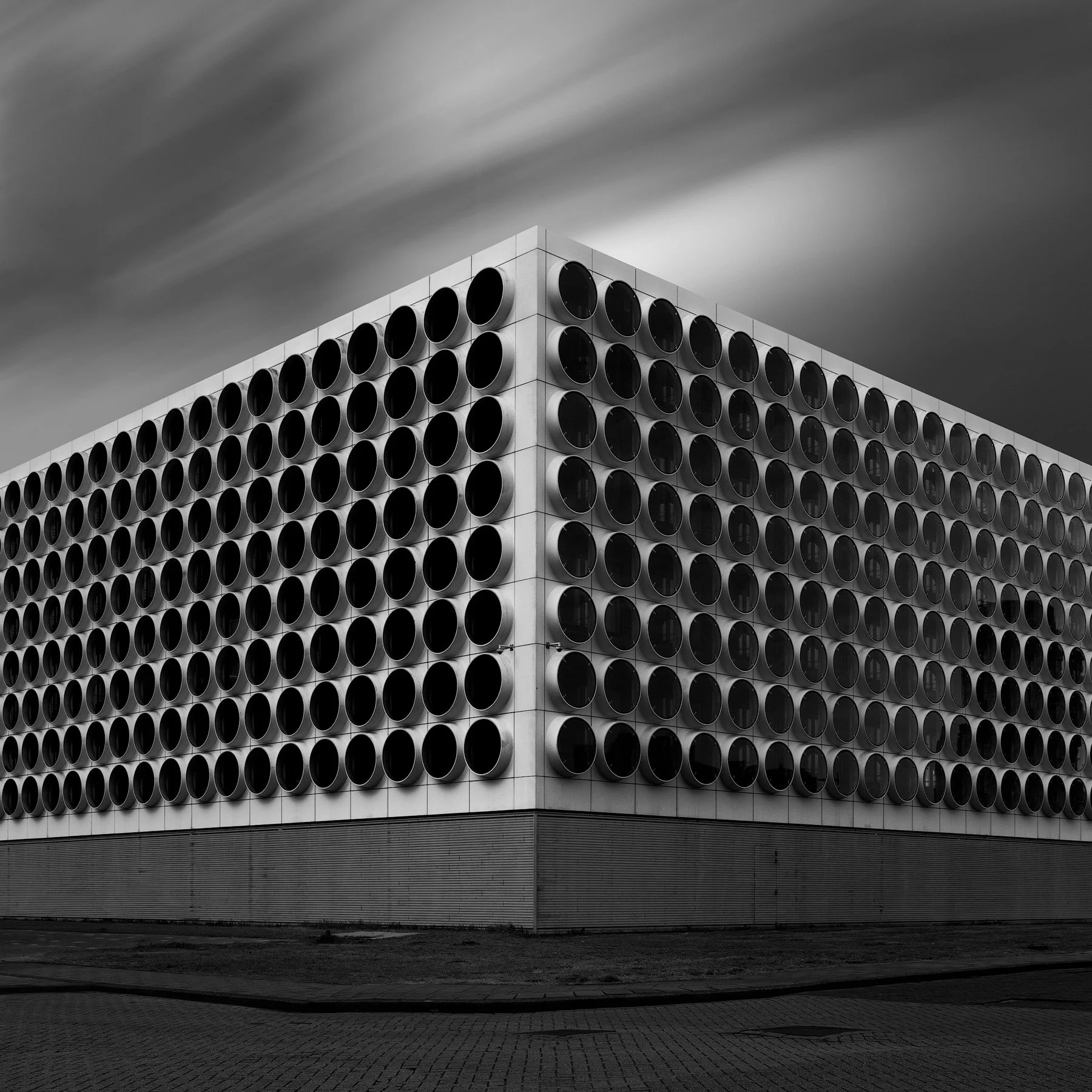 [architecture] [blackandhite] [europe] [amsterdam] [square] Monochrome image of a modernist Amsterdam building with circular porthole window grid, corner perspective. Architectural Photography by Jim Scott.