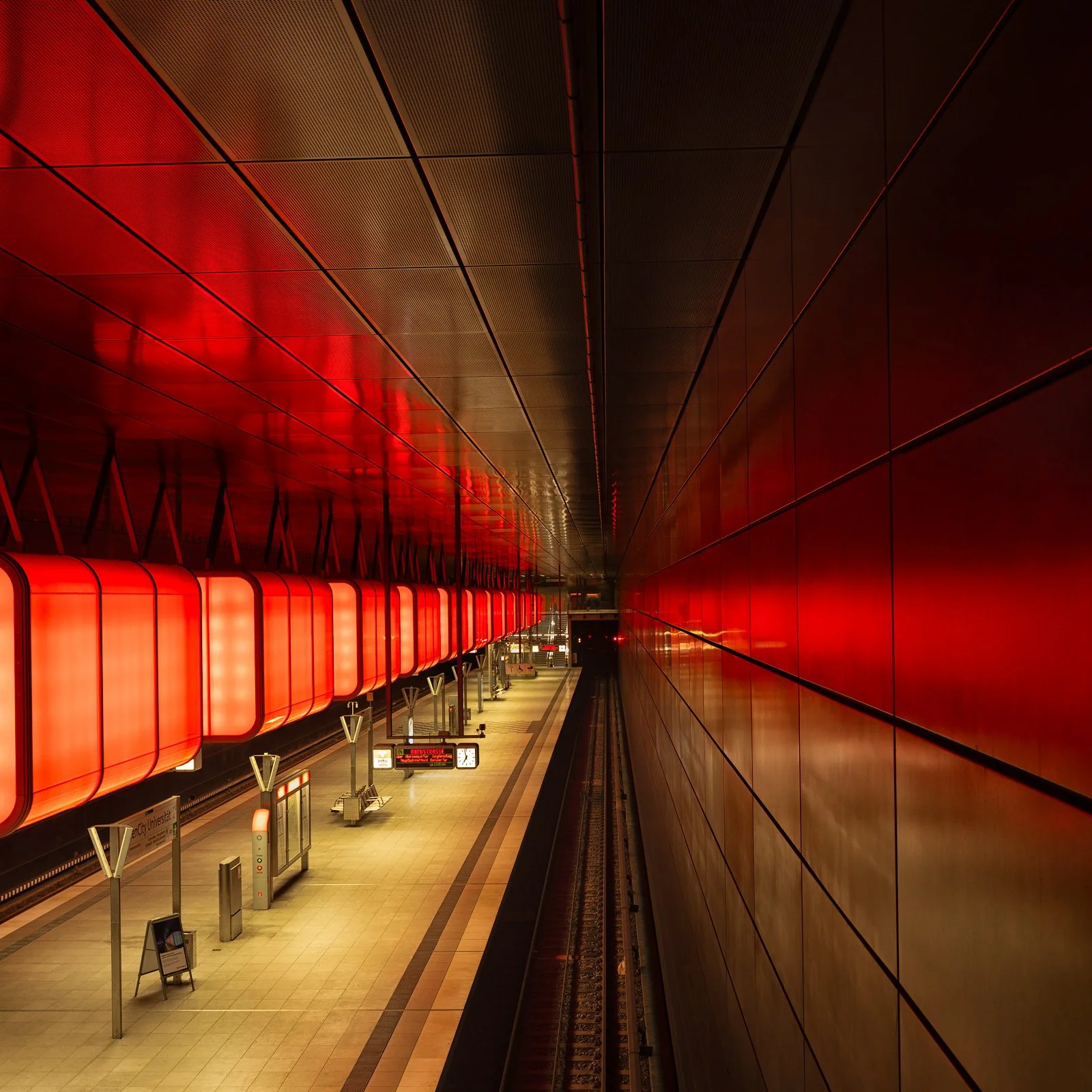 Futuristic transit design in Hamburg, Germany: A cinematic wide-angle study of the HafenCity Universität Underground Station, designed by Raupach Architekten. This architectural photograph captures the station’s iconic LED-illuminated light container