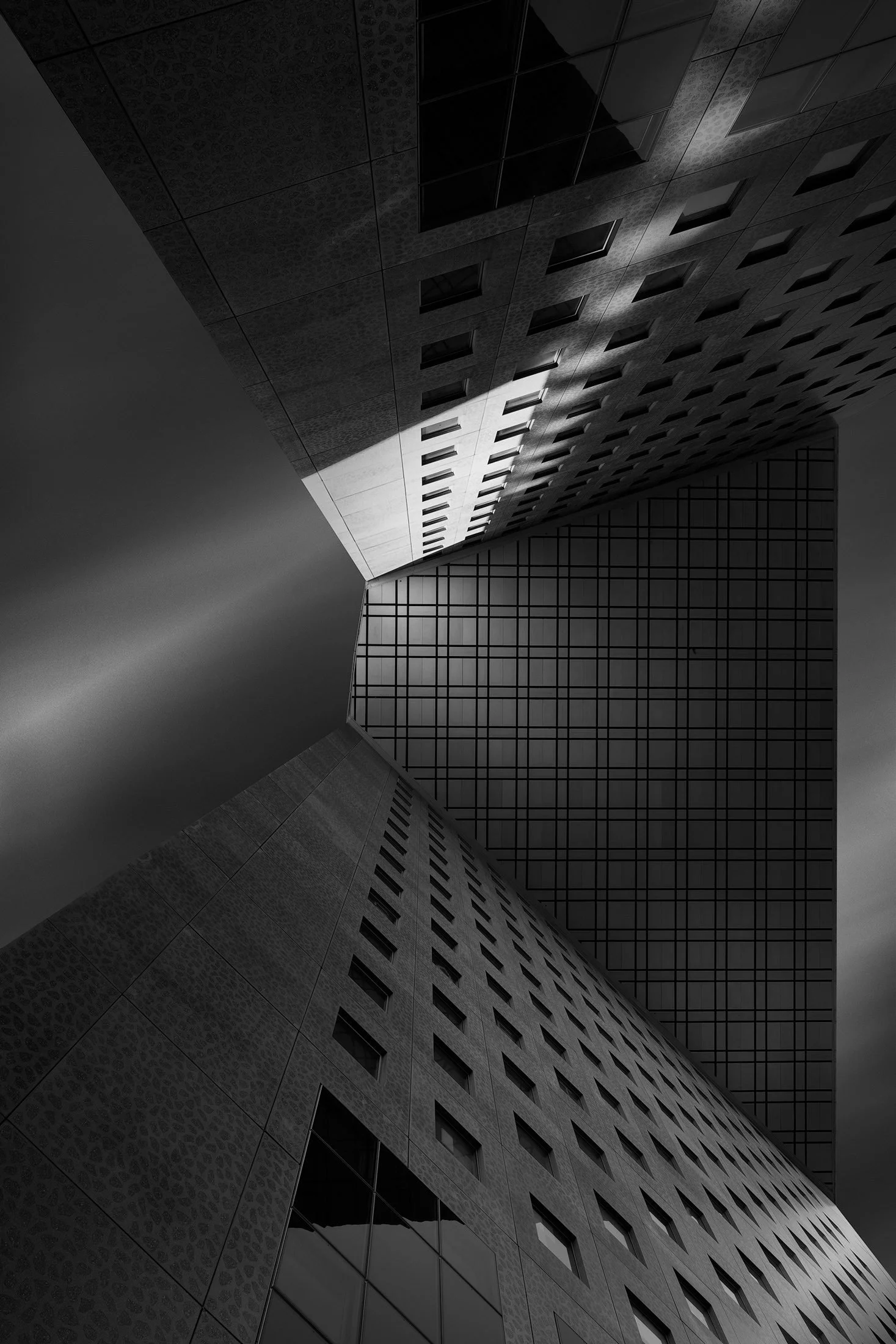 [architecture] [europe] [paris] [blackandwhite] La Defense Paris abstract upward monochrome, two angular concrete tower faces and perforated facade under a moody sky. Architectural Photography by Jim Scott.
