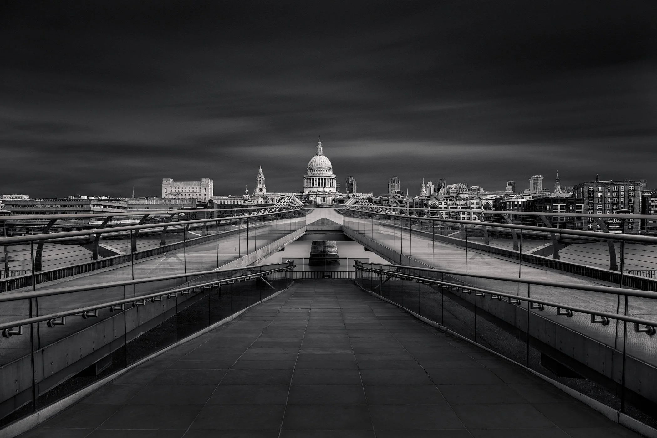[architecture] [uk] [london] [blackandwhite] London's Millennium Bridge central composition, symmetrical stainless steel walkway receding toward St Paul's Cathedral. Architectural Photography by Jim Scott.