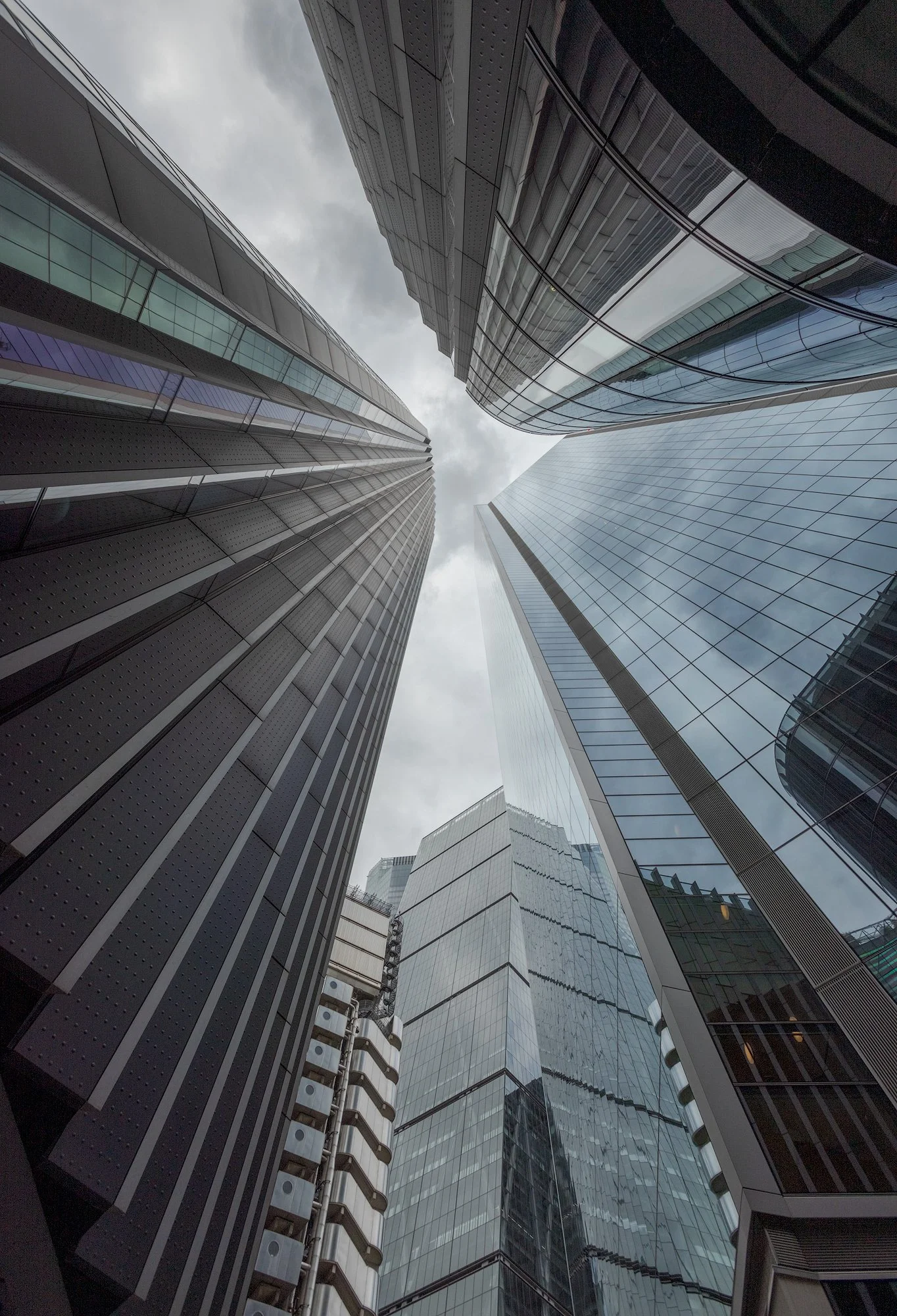 Contemporary high-rise architecture in the City of London: A dramatic low-angle upward perspective of the "Eastern Cluster" skyscrapers, featuring The Leadenhall Building (The Cheesegrater) and The Scalpel. This colour architectural image highlights 