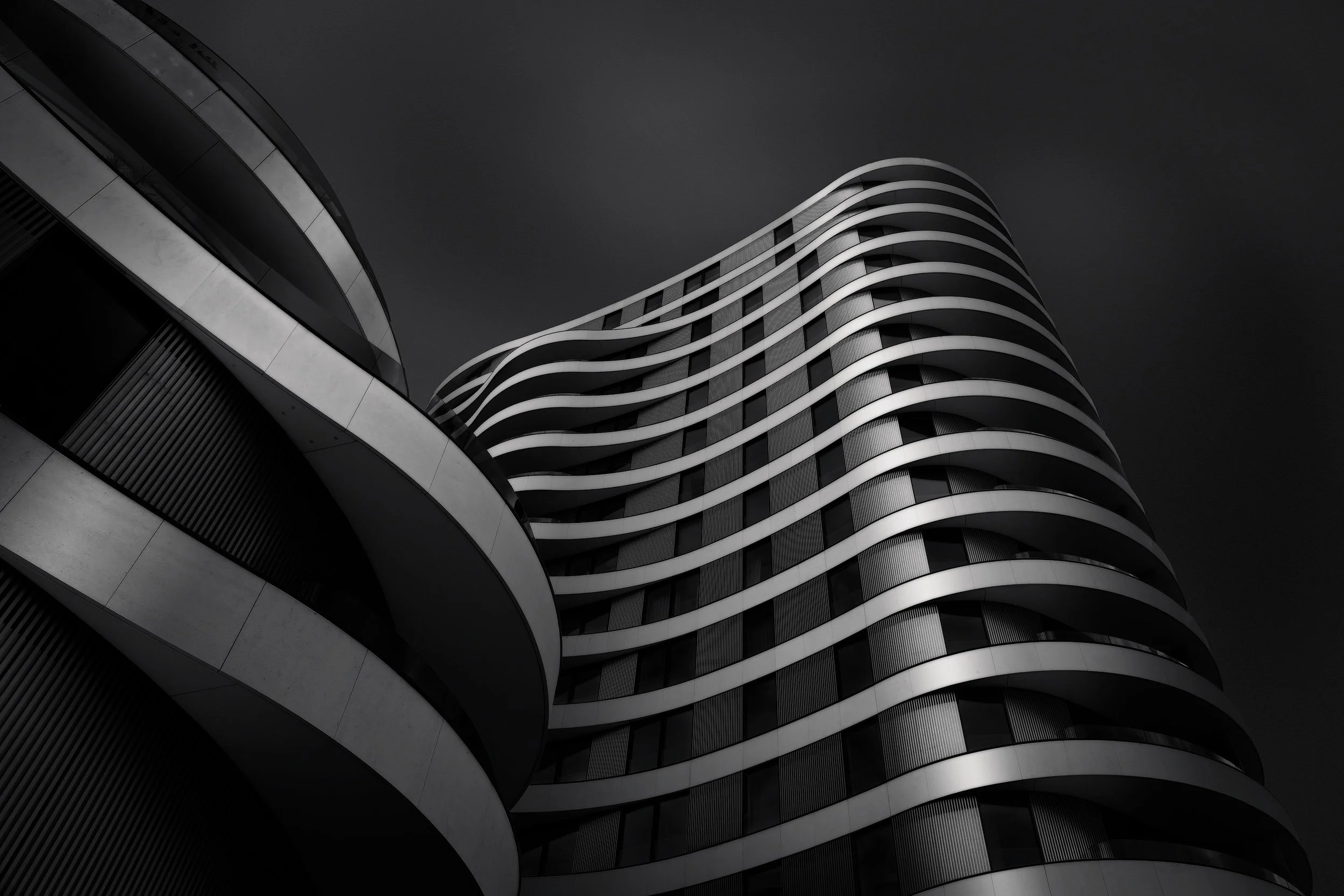 [architecture] [uk] [london] [blackandwhite] Riverwalk Apartments London upward monochrome, sensuous wave-form horizontal balcony bands undulating against dark sky. Architectural Photography by Jim Scott.