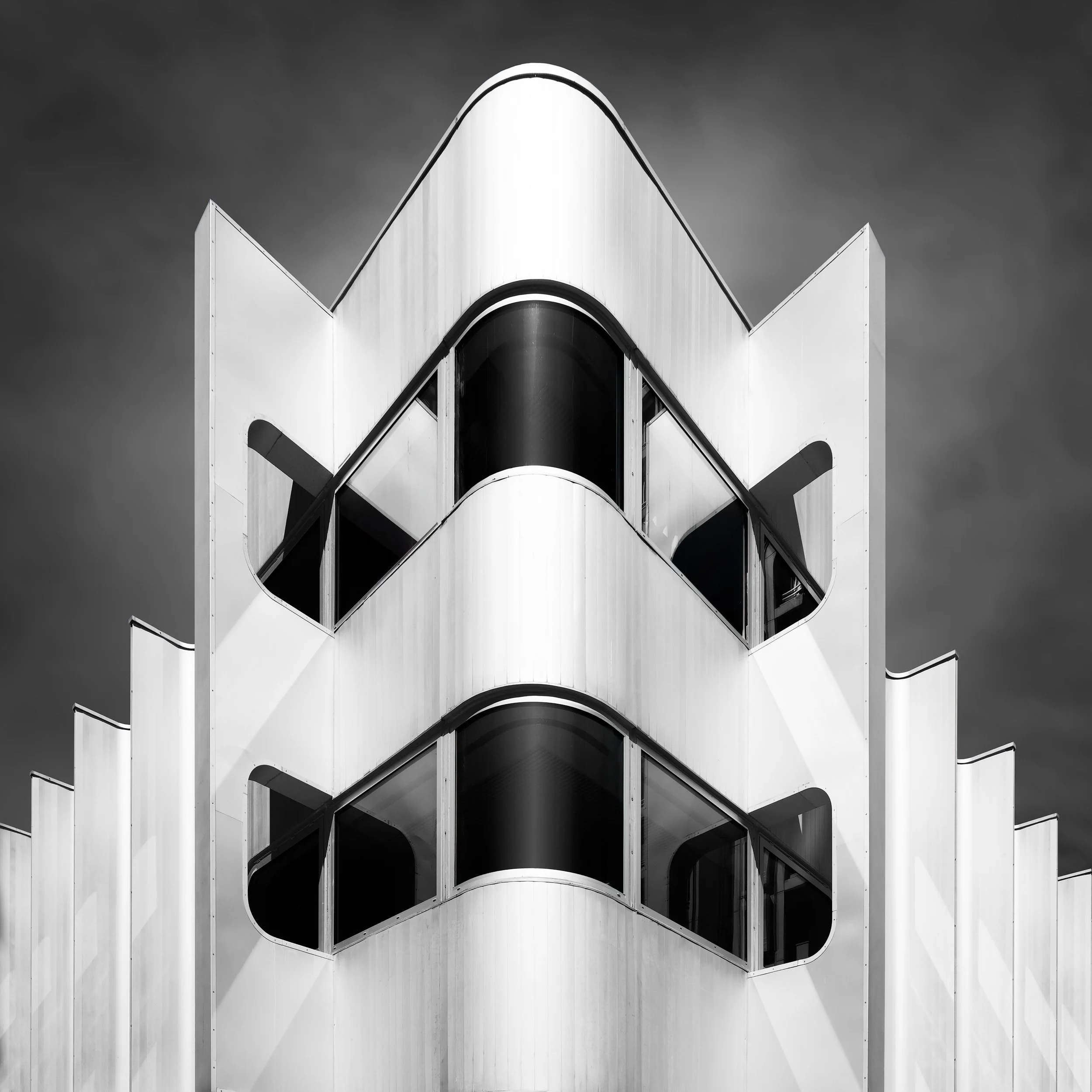 Contemporary urban abstraction in Paris, France: A symmetrical monochromatic study of the Beaugrenelle building, designed by Valode & Pistre. This architectural photograph captures the rhythmic, fluid geometry of the metallic facade and its distincti