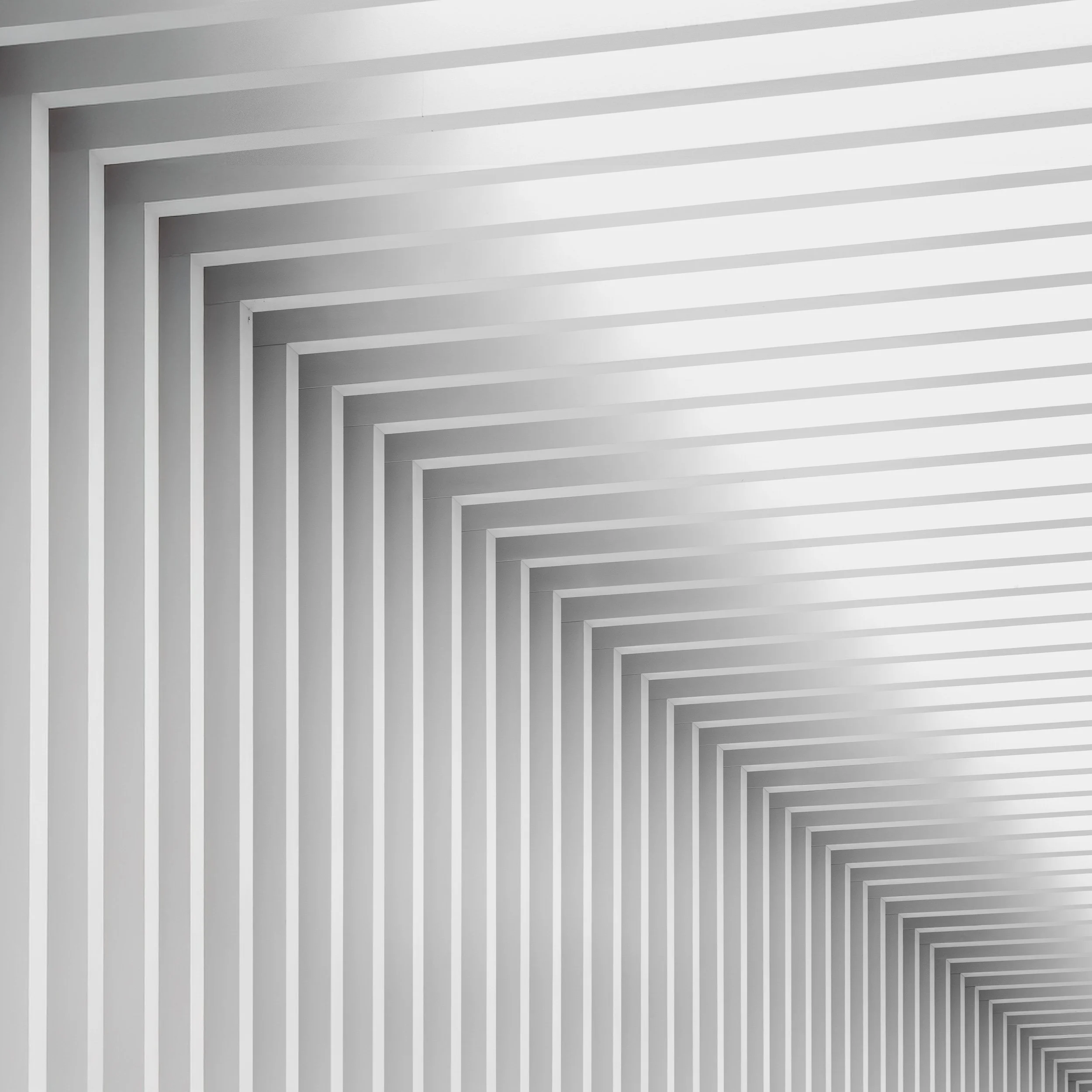 Minimalist interior architecture in Birmingham, England: A high-key abstract study of the geometric patterns within The Mailbox, designed by Associated Architects. This monochromatic photograph emphasises the rhythmic repetition of linear forms and s