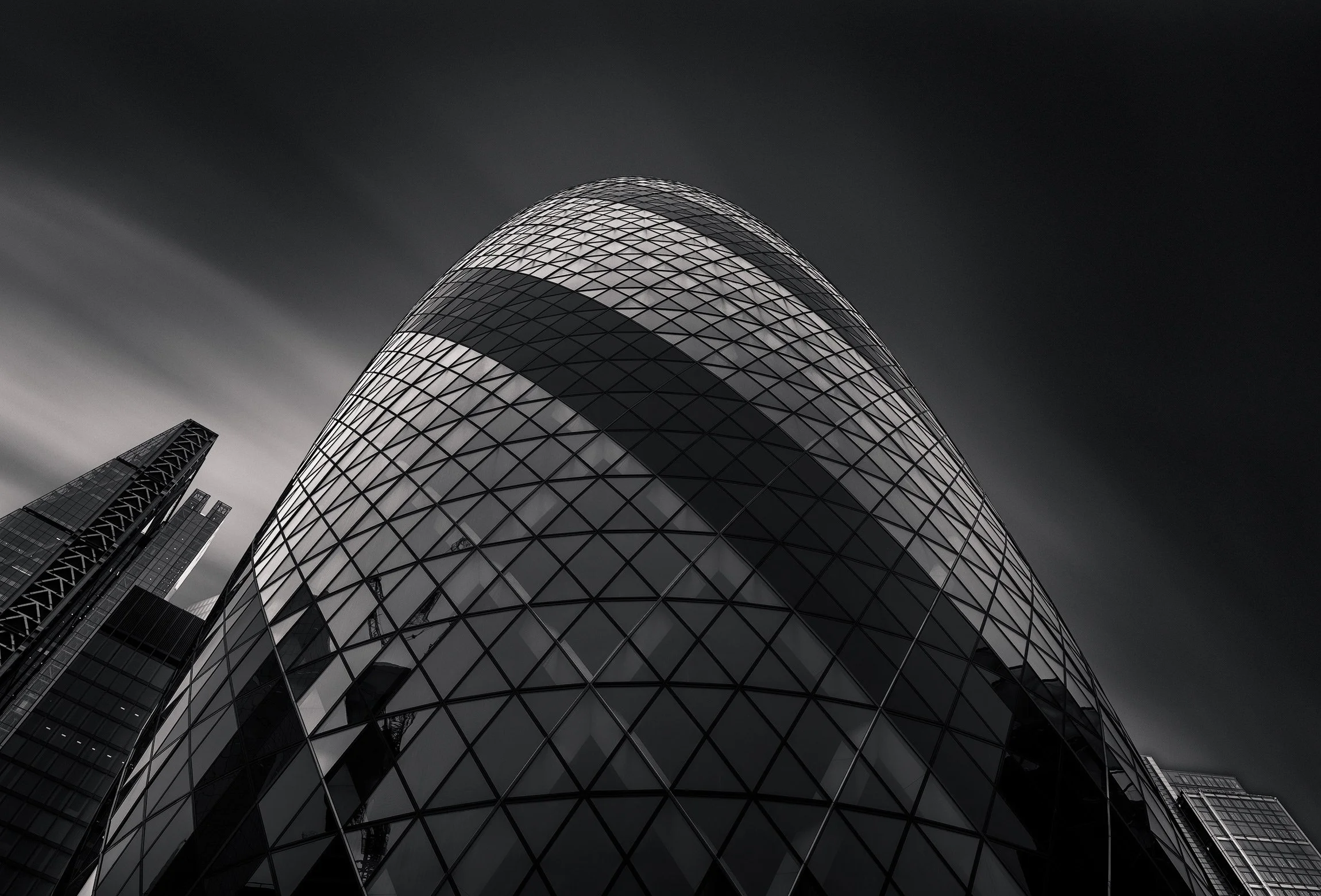 [architecture] [uk] [london] [blackandwhite] 30 St Mary Axe Gherkin London, close upward view of bulging diamond glazed dome with Leadenhall visible, long exposure atmospheric. Architectural Photography by Jim Scott.
