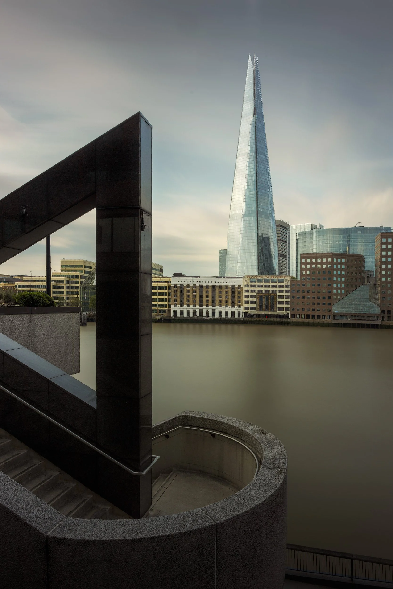Contemporary architecture in London: The Shard (London Bridge Tower) designed by Renzo Piano, rising above the historic brick facades of London Bridge City. A low-angle black and white photograph highlighting the sharp, tapered glass "shards" as they