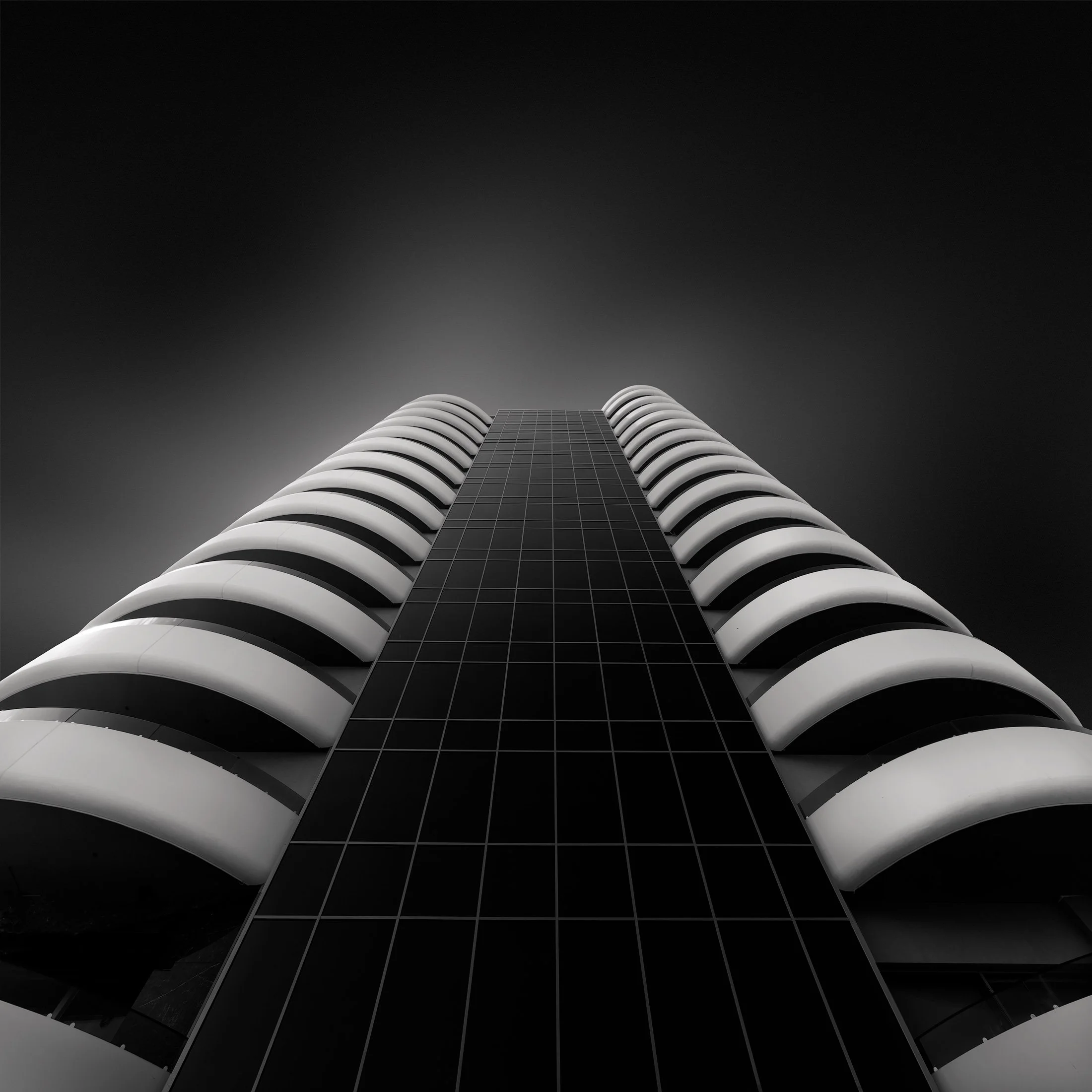 Contemporary architecture in Benidorm, Spain: The Hotel Gold Arcos designed by JAS Arquitectura (José Manuel Escobedo Pérez). A high-contrast black and white architectural study of the 22-story tower, highlighting its undulating white balconies and f