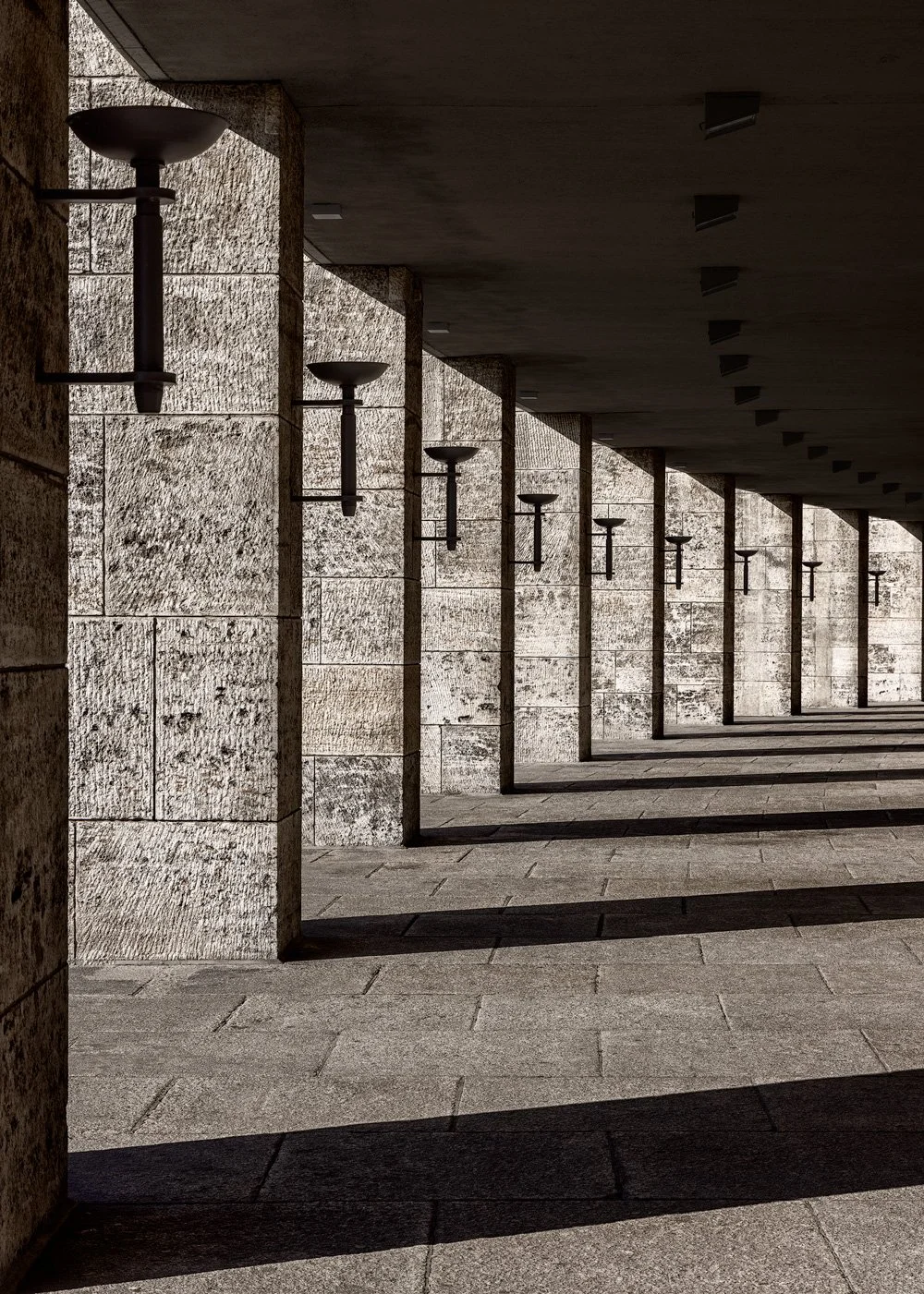 [architecture] [europe] [Berlin] [colour] [abstract] A receding stone colonnade lined with lantern-topped columns stretches along Berlin's Olympiastadion. Architectural Photography by Jim Scott