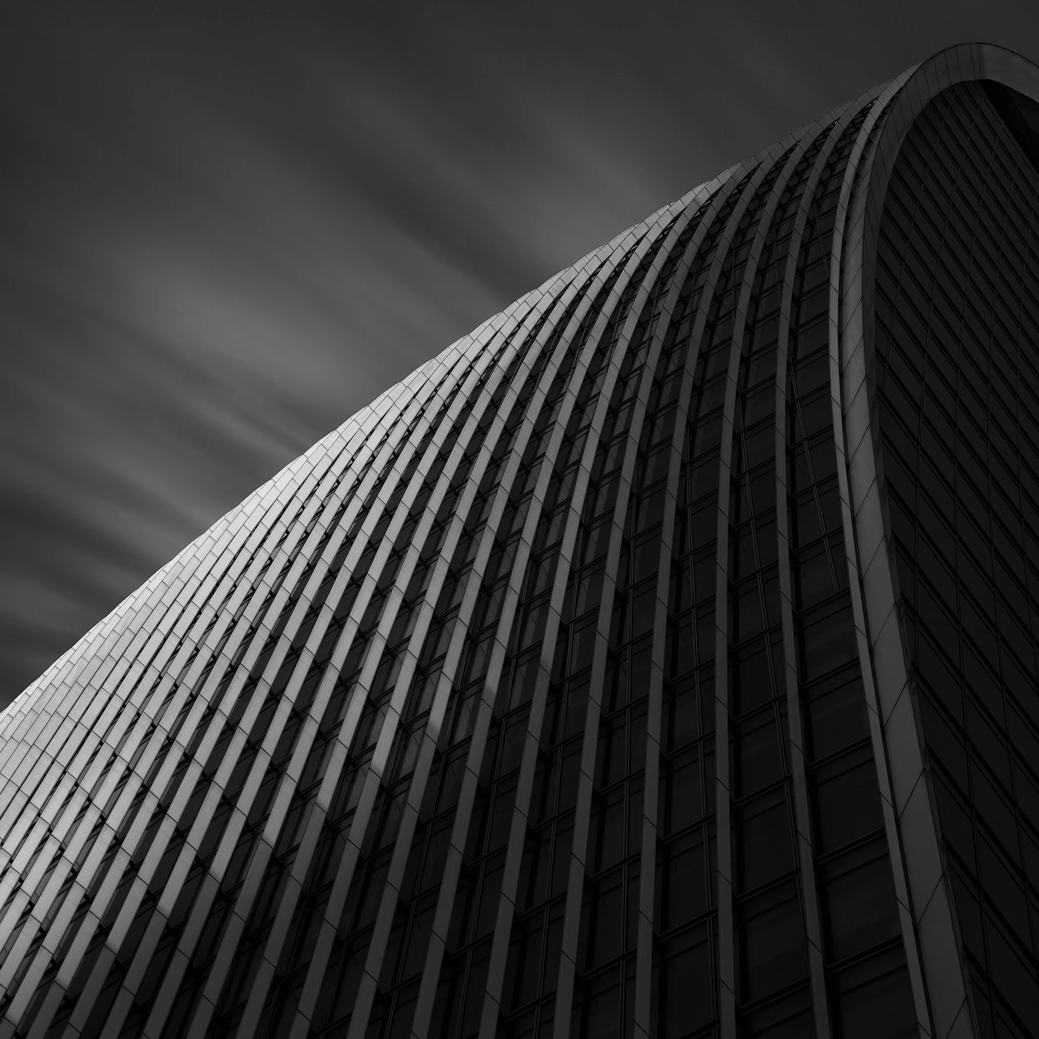 Contemporary architecture in the City of London: A dramatic black and white abstract of 20 Fenchurch Street (The Walkie-Talkie), designed by Rafael Viñoly. A high-contrast long-exposure photograph focusing on the building’s signature flared glass fac