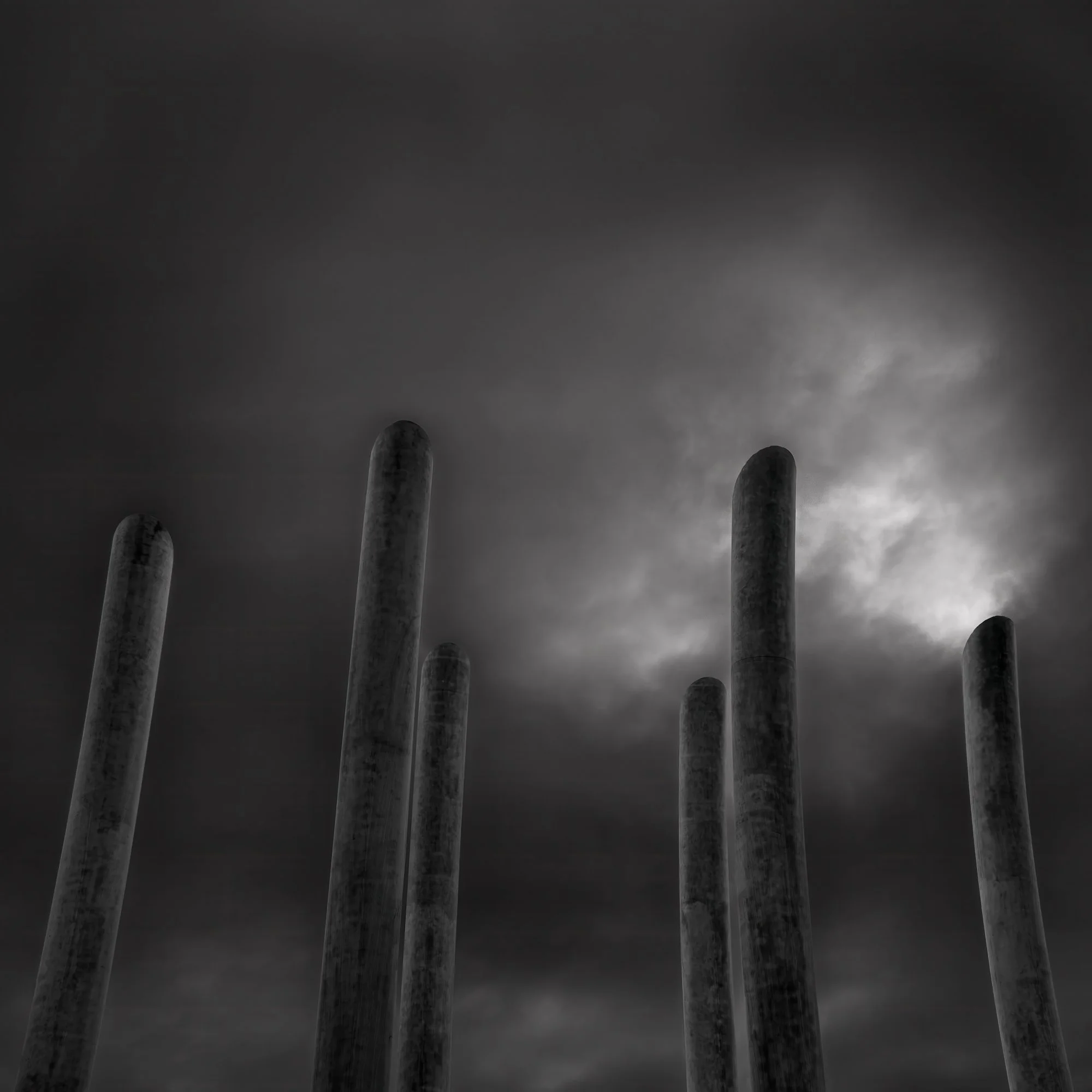 [architecture] [uk] [blackpool] [blackandwhite] [square] High Tide Organ Blackpool, six weathered concrete pipes of varying heights rising against a brooding dark storm sky. Architectural Photography by Jim Scott.