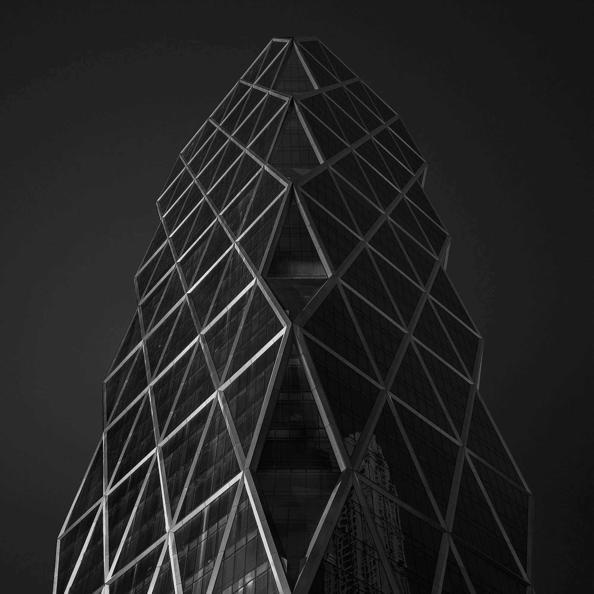 [architecture] [global] [newyork] [blackandwhite] Hearst Tower New York monochrome, triangulated steel diagrid curtain wall tapering to a sharp apex against dark sky. Architectural Photography by Jim Scott.