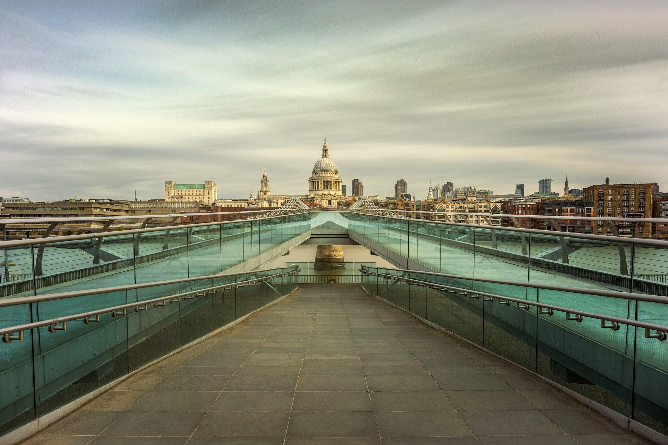 [architecture] [uk] [london] [colour] On-bridge composition along the empty Millennium Bridge London, glass rails converging toward St Paul's Cathedral. Architectural Photography by Jim Scott.