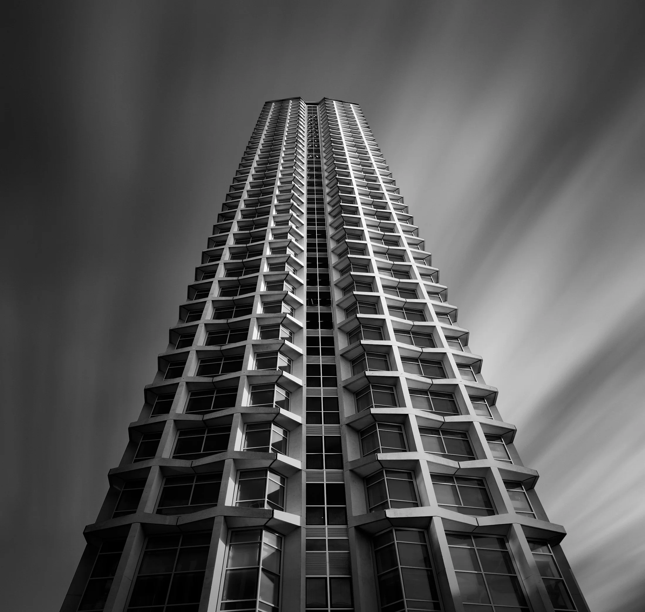 [architecture] [uk] [london] [blackandwhite] [square] Centre Point London upward long exposure, Brutalist concrete tower's precast hexagonal grid tapering to the sky. Architectural Photography by Jim Scott.