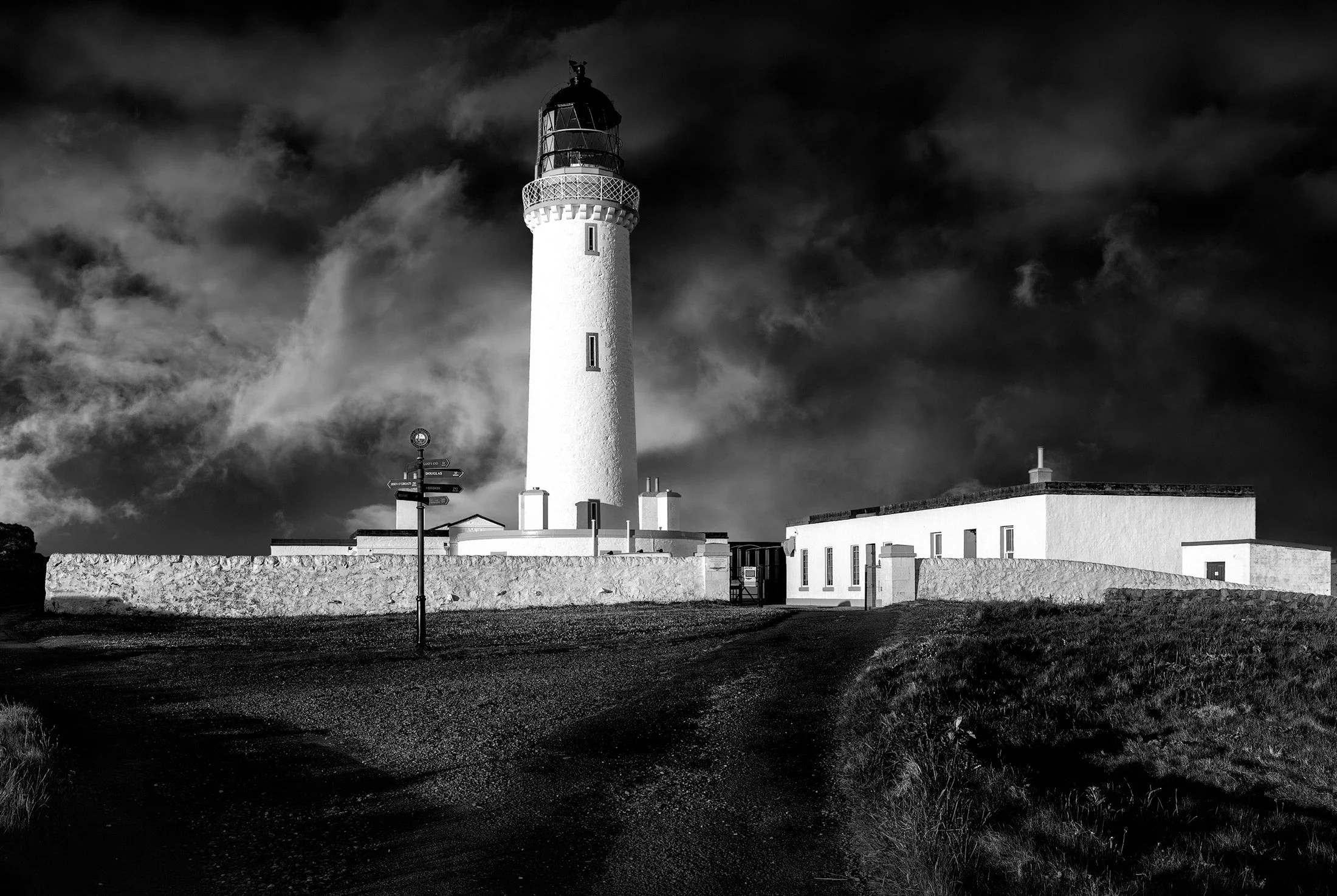 [architecture] [uk] [mullofgalloway] [blackandwhite] Mull of Galloway lighthouse whitewashed tower with keeper's cottages and stone wall, dramatic monochrome landscape. Architectural Photography by Jim Scott.