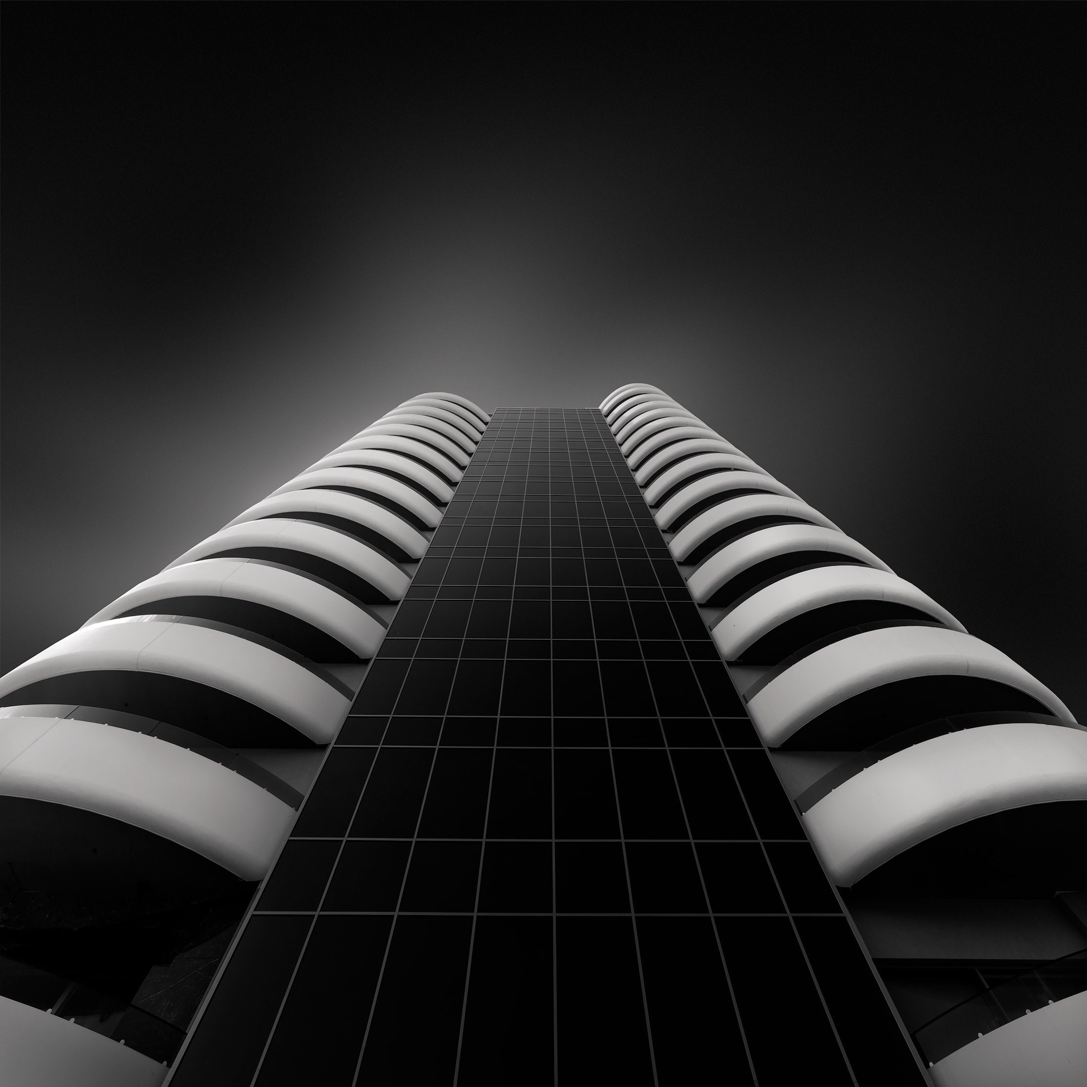 [architecture] [europe] [benidorm] [ blackandwhite] [square] Hotel Gold Arcos Benidorm dramatic upward monochrome, dark glazed facade flanked by symmetrical curved white balcony. Architectural Photography by Jim Scott.