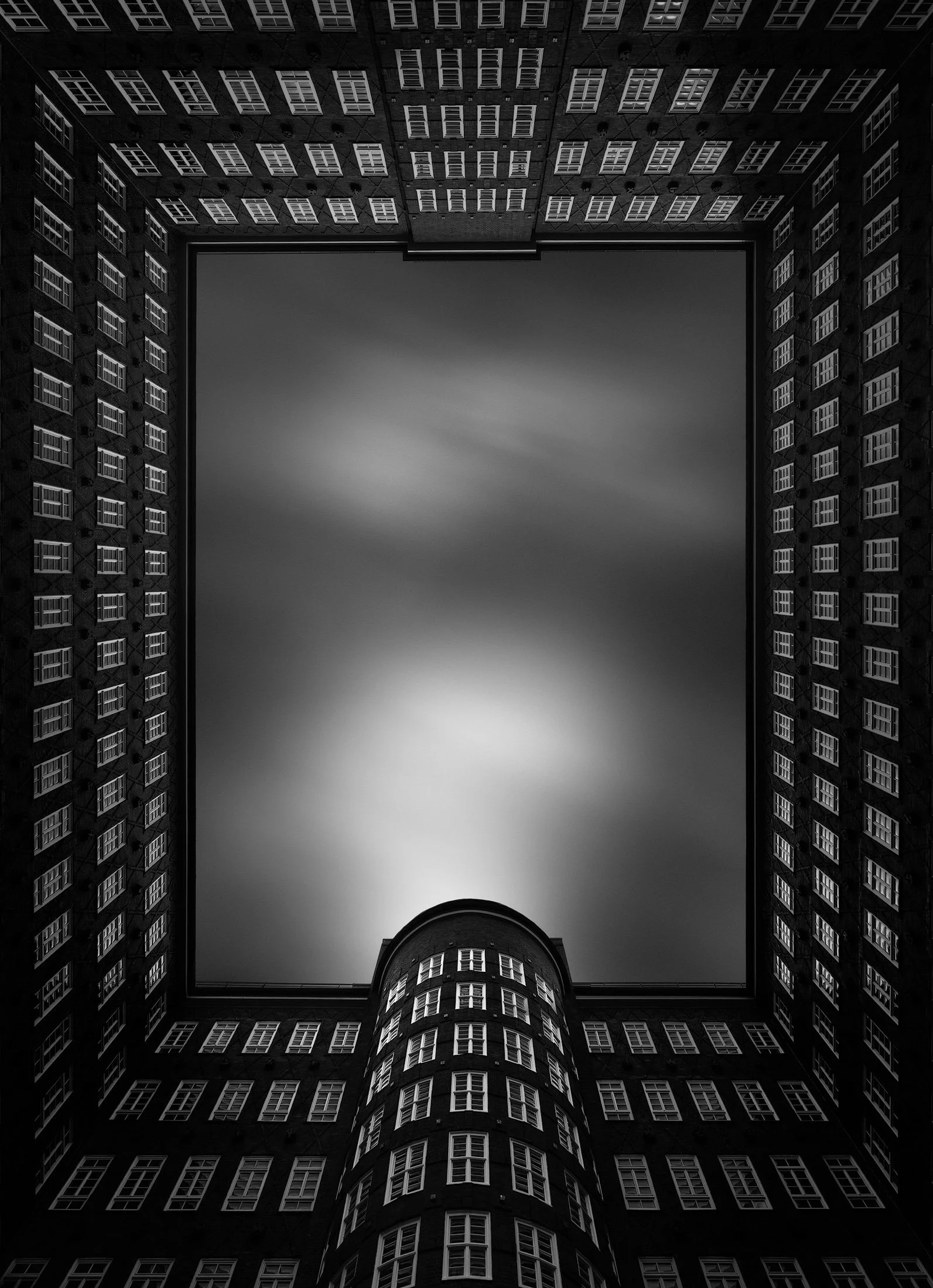 Brick Expressionist architecture in Hamburg, Germany: A dramatic monochromatic study of the Sprinkenhof, designed by Fritz Höger and Gropius & Schmacker. This architectural photograph captures the internal courtyard from a vertical, ground-up perspec