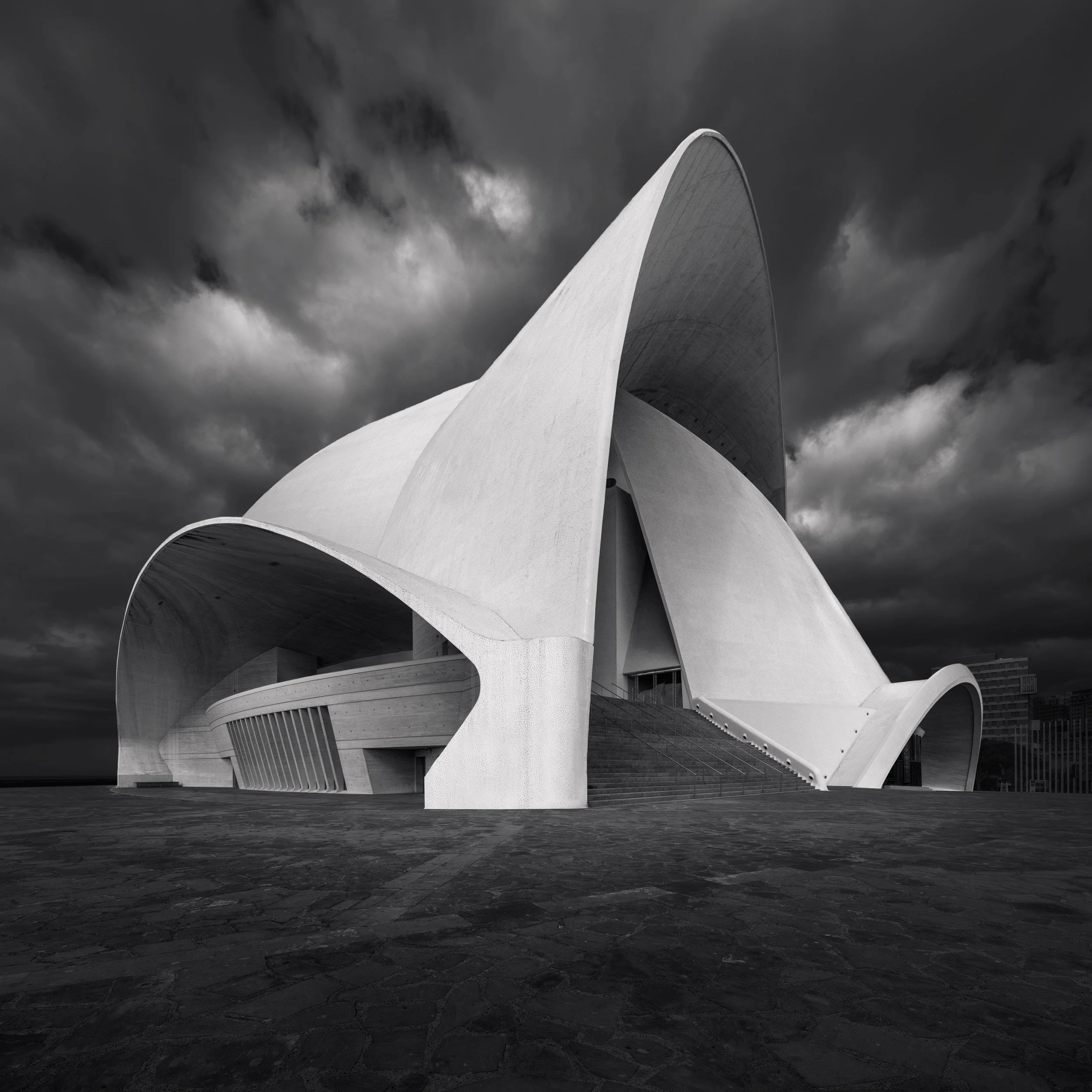 [architecture] [europe] [santacruzdetenerife] [blackandwhite] [square] Auditorio de Tenerife by Calatrava, all white shell forms surging upward under a turbulent storm-filled sky. Architectural Photography by Jim Scott.