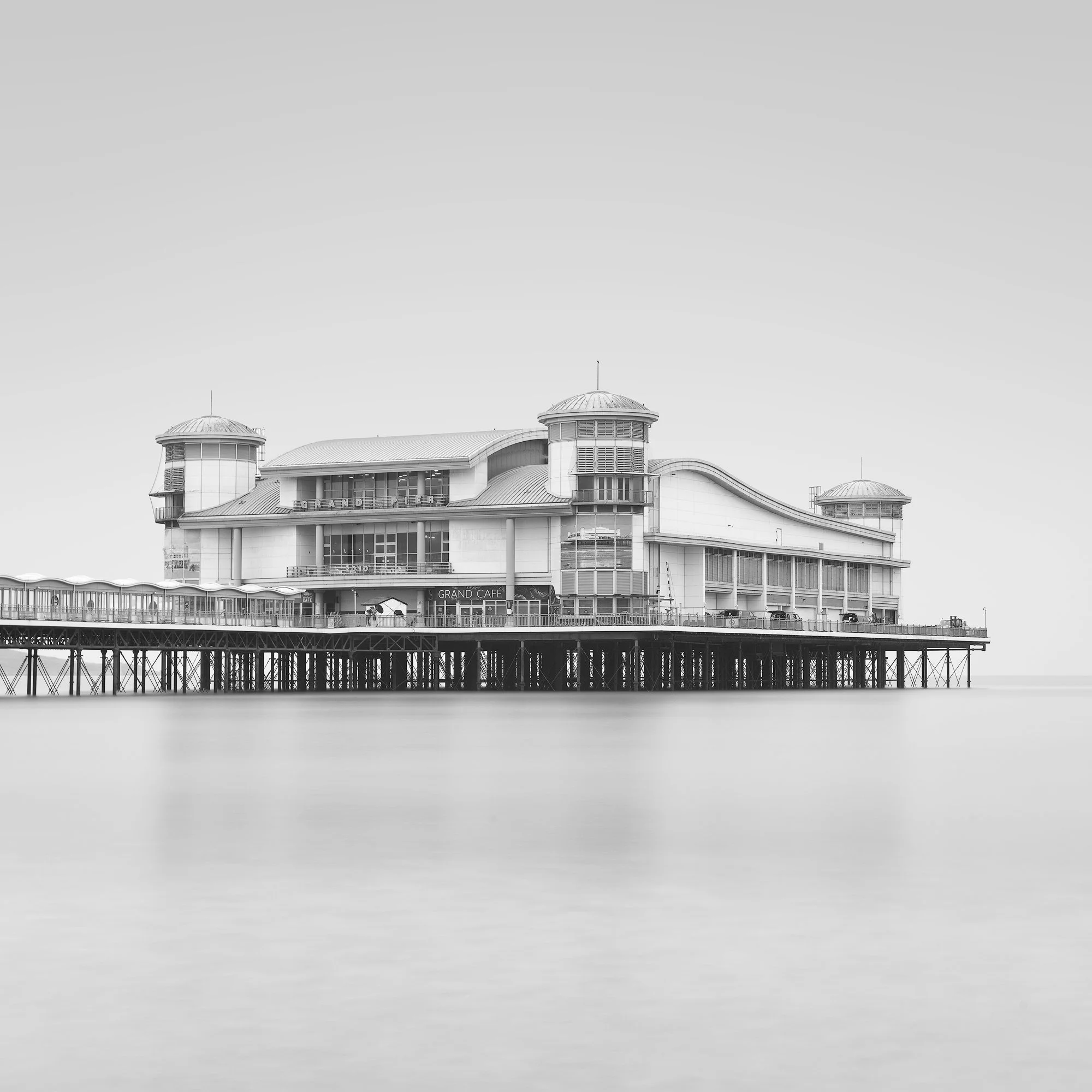 [architecture] [uk] [westonsupermare] [blackandwhite] [square] Grand Pier Weston-super-Mare B&W, Art Deco pavilion floating above iron stilts in a silk-smooth pale misty sea. Architectural Photography by Jim Scott.